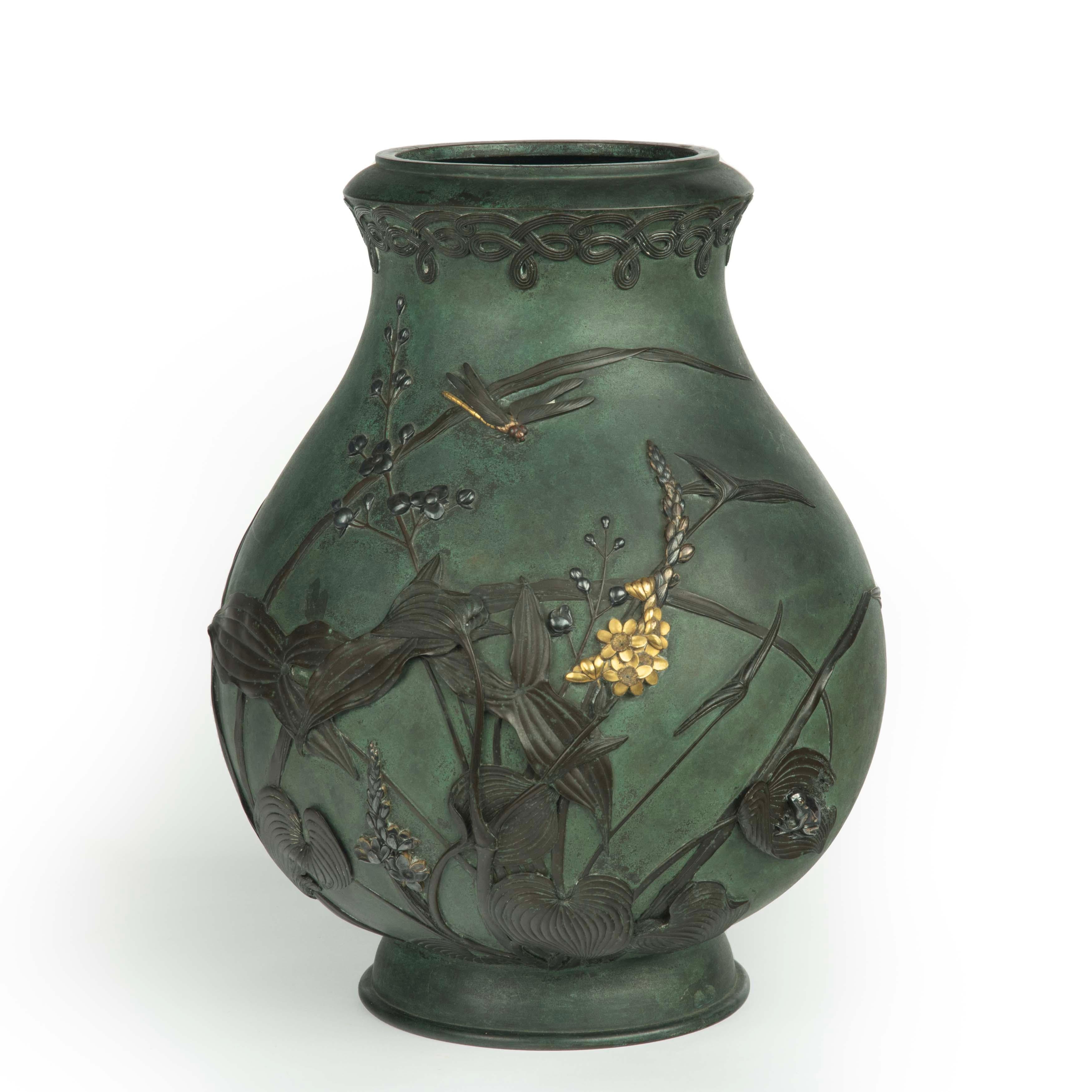 Vase en bronze patiné de la période Meiji par Kiryu Kosho Kaisha. Le corps balustre est orné de motifs en or, en argent, en bronze et en cuivre représentant des plantes de la famille des fèves et des pointes de flèche, ainsi qu'une grenouille, une