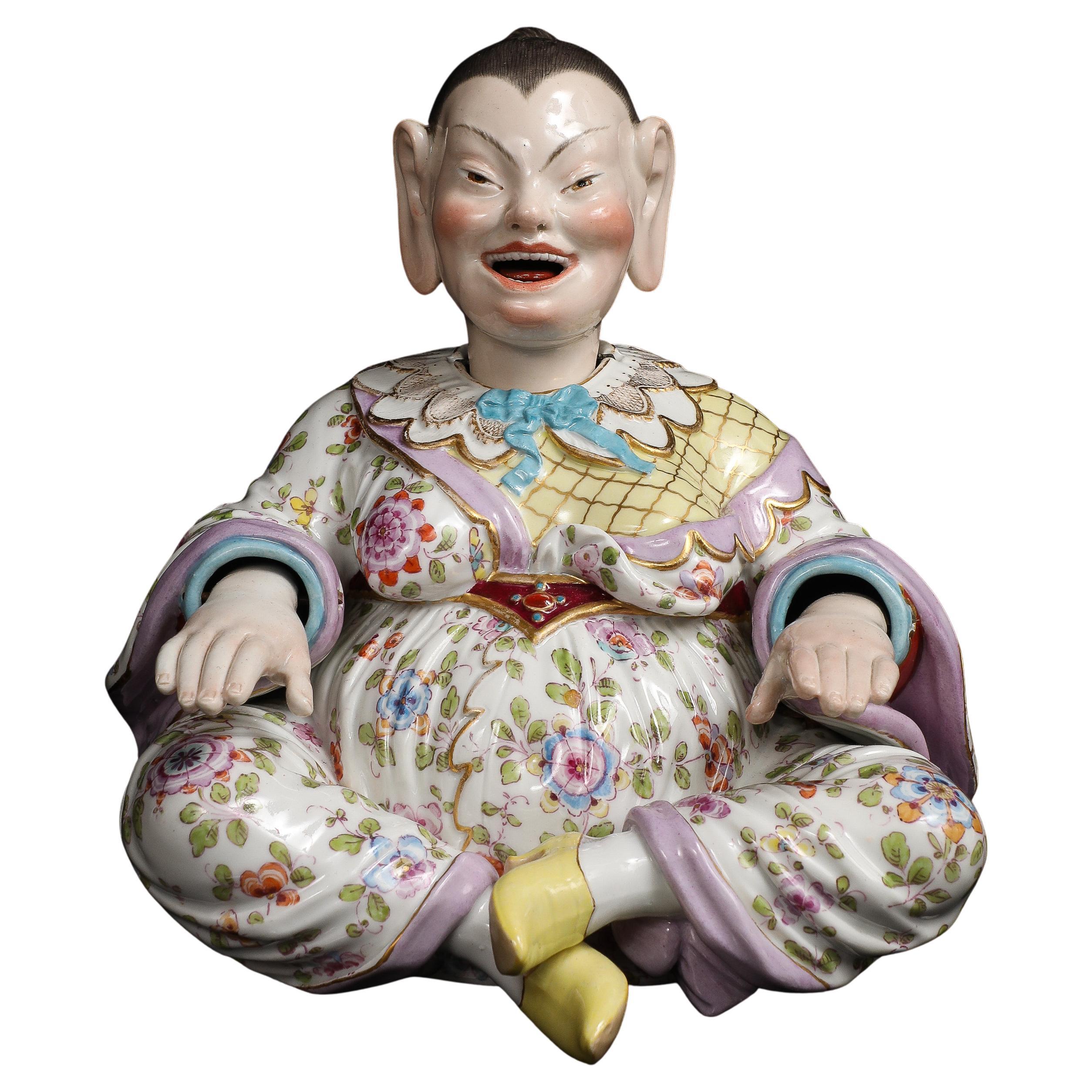 Eine Wackelkopffigur aus Meissener Porzellan des 19. Jahrhunderts, modelliert als sitzende Pagodenfigur, mit Kopf und Händen, die durch innere Gegengewichte beweglich sind. Die Unterseite ist mit den unterglasurblauen gekreuzten Schwertern der