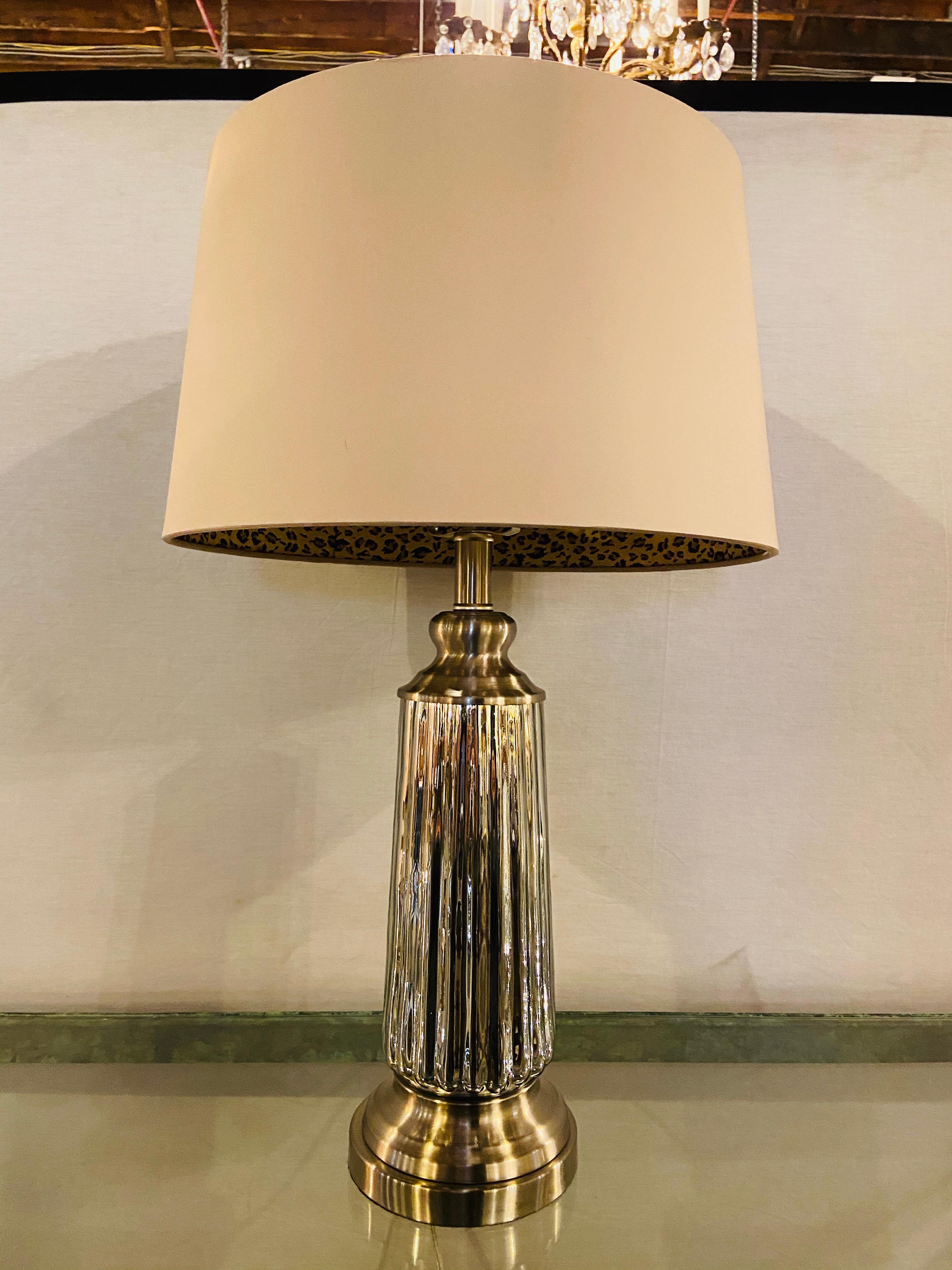 A Simple and chic Mid Century Modern style table lamp.  The silver tone lamp features a ribbed design and embellished with a custom shade having  leopard pattern interior.

Dimensions:
Lamp is 26