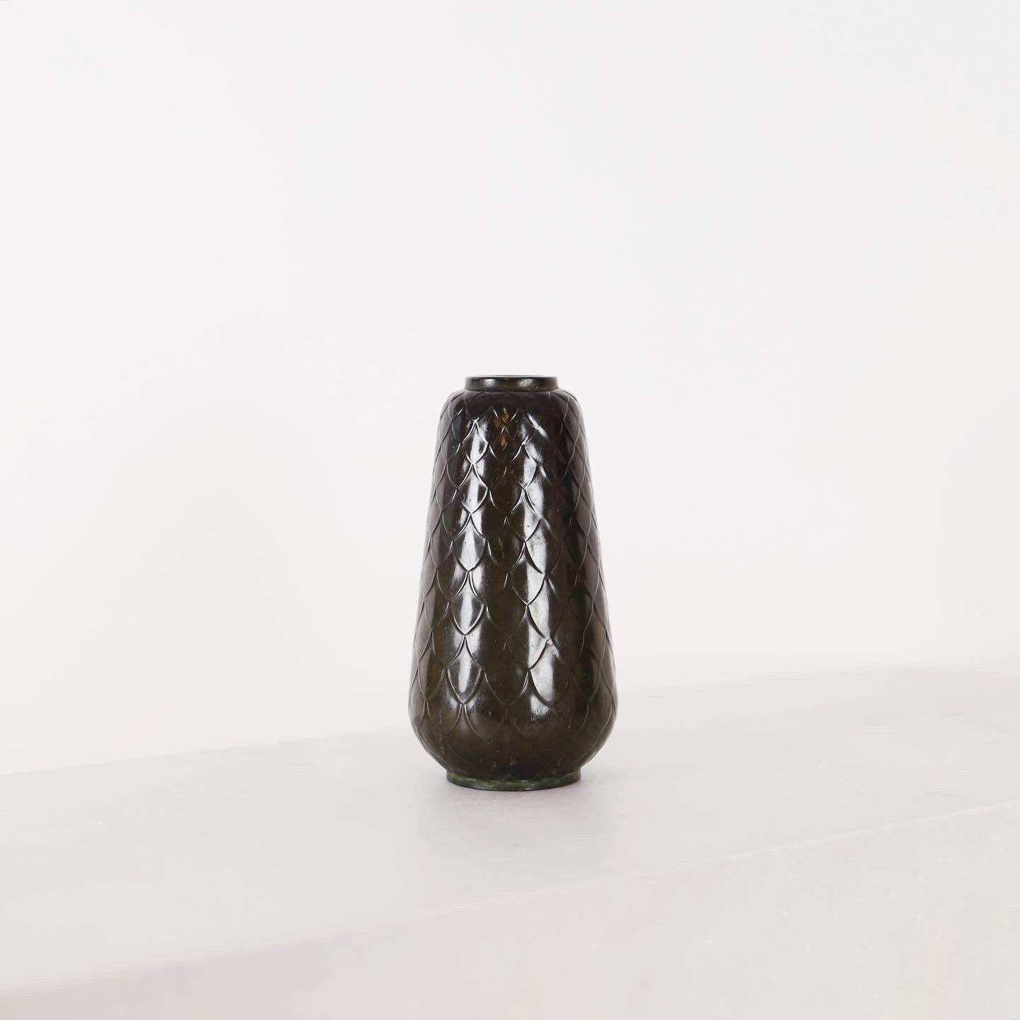 Un vase disco en métal avec un motif en peau de serpent, conçu par Ellen Schlanbush, qui fut avant l'heure directrice artistique de Just Andersen. 

* Un vase en métal avec un motif de peau de serpent 
* Designer : Ellen Schlanbusch
* Fabricant :