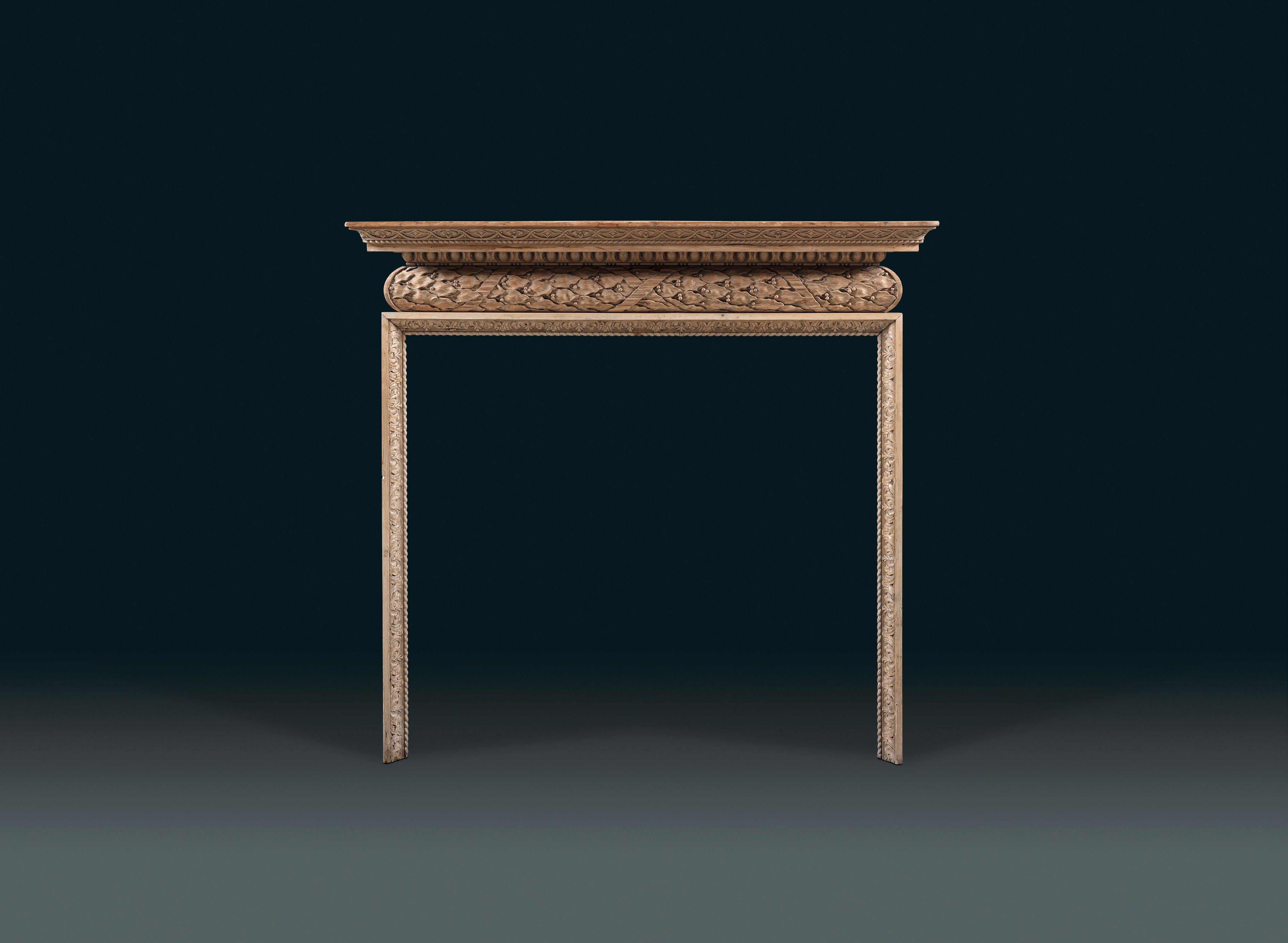A mid-18th century carved pine chimneypiece, the moulded shelf richly carved with Egg & Dart, above a barrel frieze carved with running laurel bound in ribbon, unusually running left – to – right rather than symmetrically from the centre.