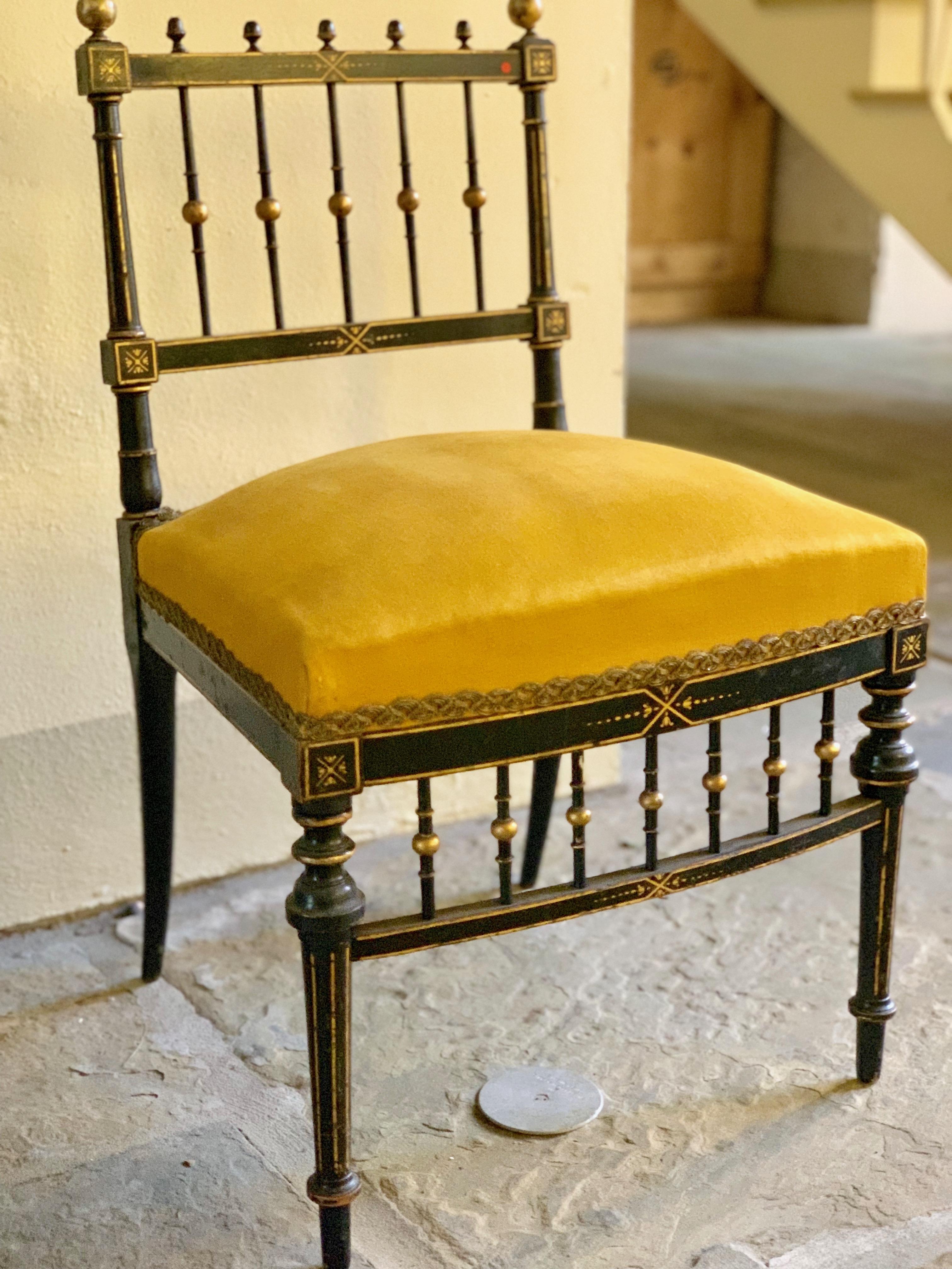 A French chair created circa 1750 in the style of ornate art furniture. The wood is ebonized fruitwood with gilded accents. The legs are tapered and turned, finished with giltwood accents. The golden cushion is finished with embroidered trim,