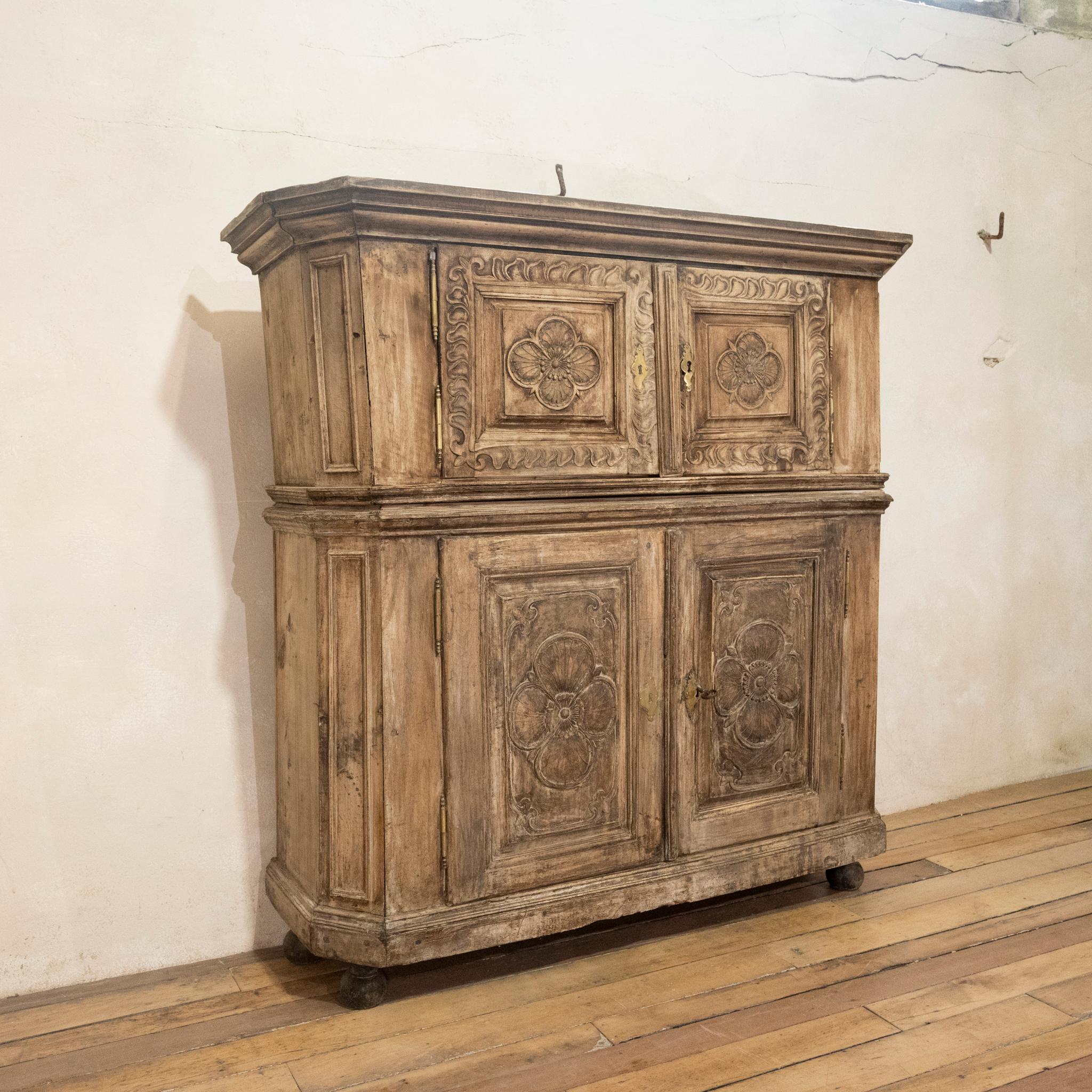 A 'square' mid 18th century and later French walnut armoire cupboard. Demonstrating a stepped cornice above a pair of raised and fielded panel doors carved with quatrefoils and flowerhead bosses. The slightly projecting base with a further pair of
