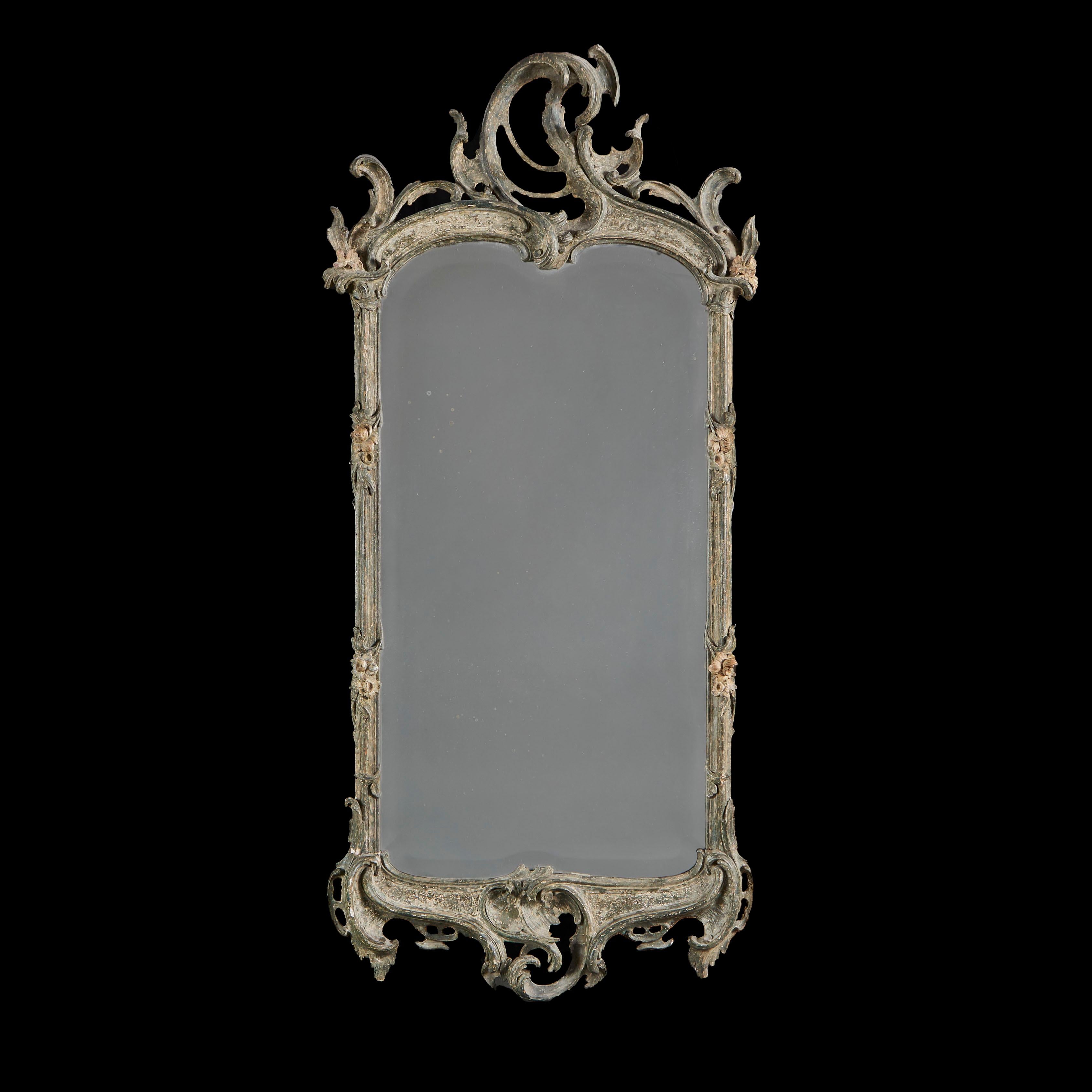 France, circa 1780

A late eighteenth century painted Rococo pier mirror retaining a bevelled plate, with mannered pierced C scroll to the cresting, the frame carved with paterae. The frame dry scraped to reveal the original blue colour painted