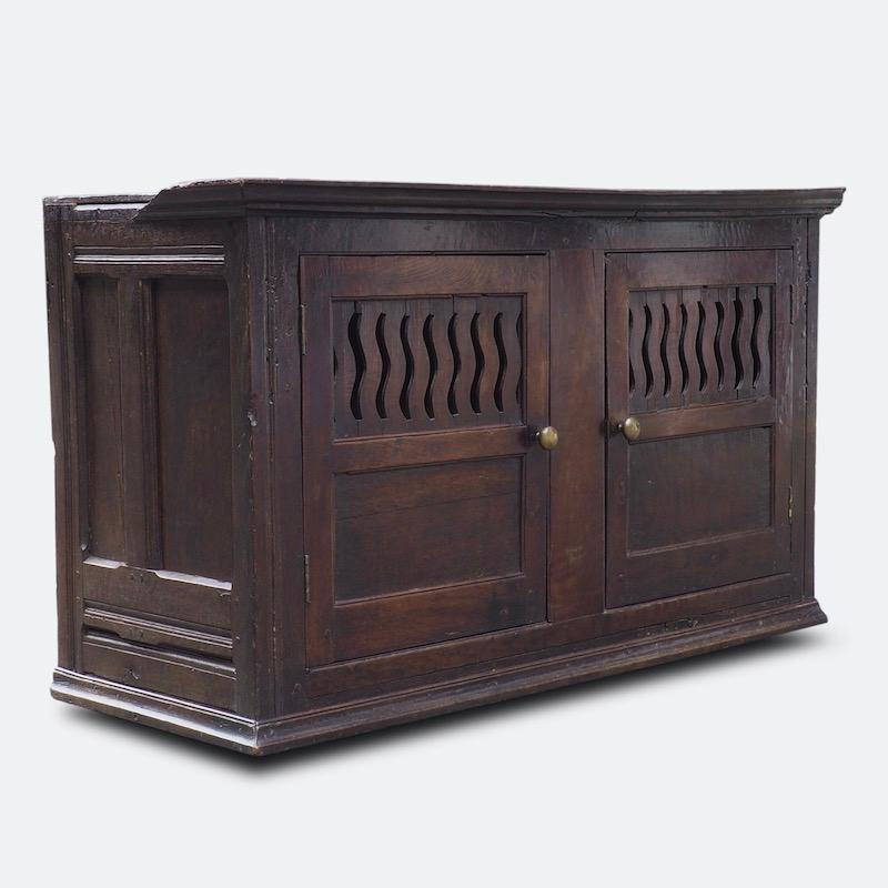 A stunning early Georgian wall-mountedcupboard, comprising of an original 18th century timber frame with double cupboard doors ventilated with two rows of eight wavy-fretted splats, typical of the early Georgian period
Often hung on the wall,