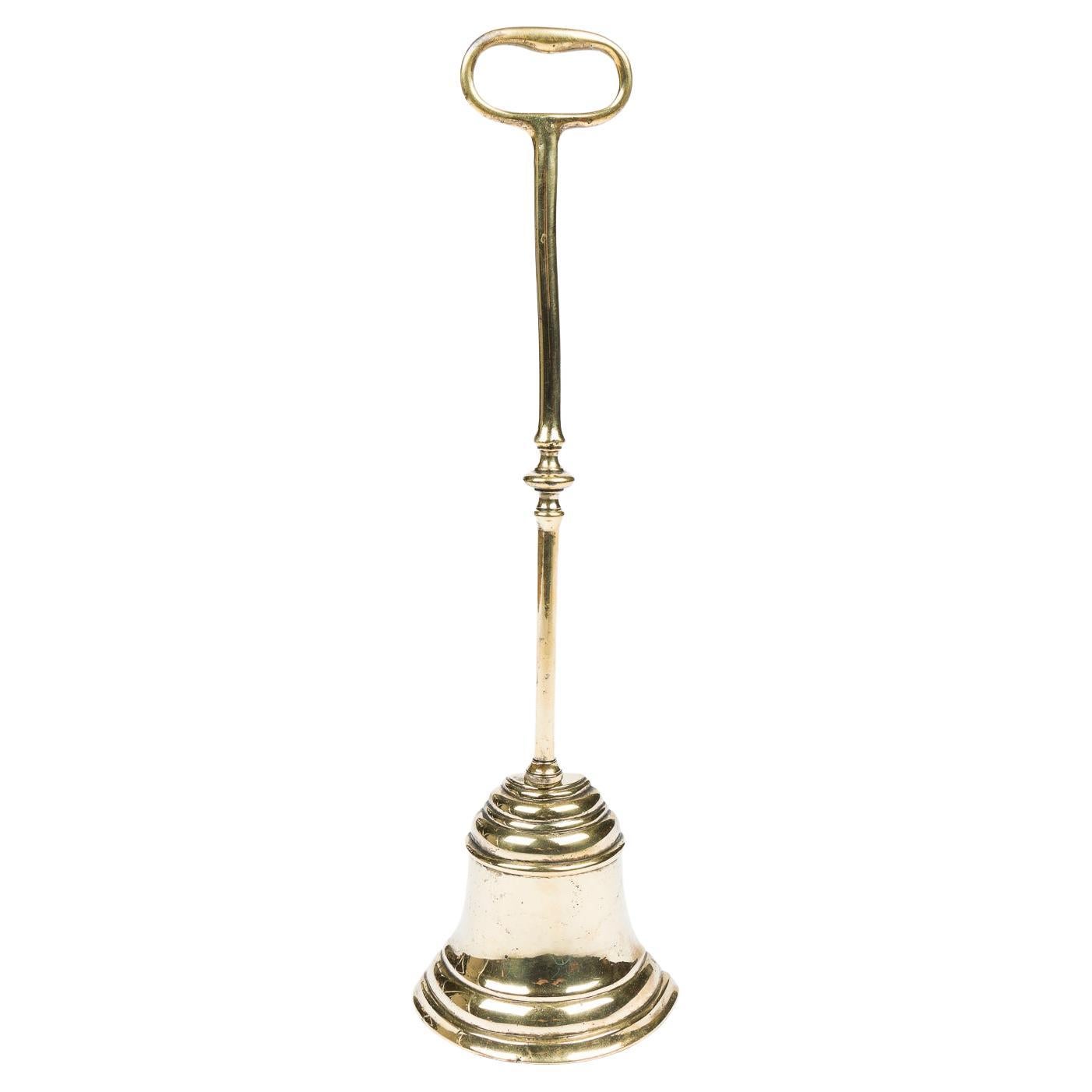 A mid 19th century brass bell shaped door stop