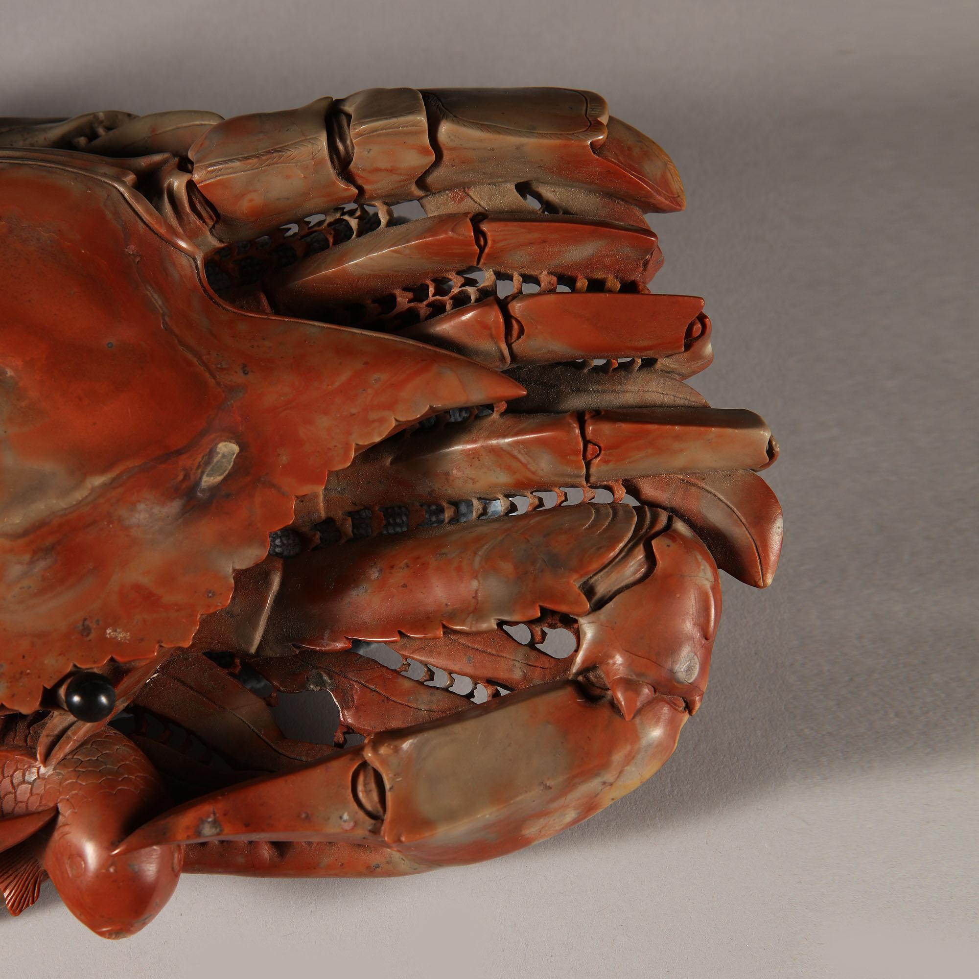 A rare mid-19th century Chinese red soapstone crab, realistically modelled with a carp in the front claws.