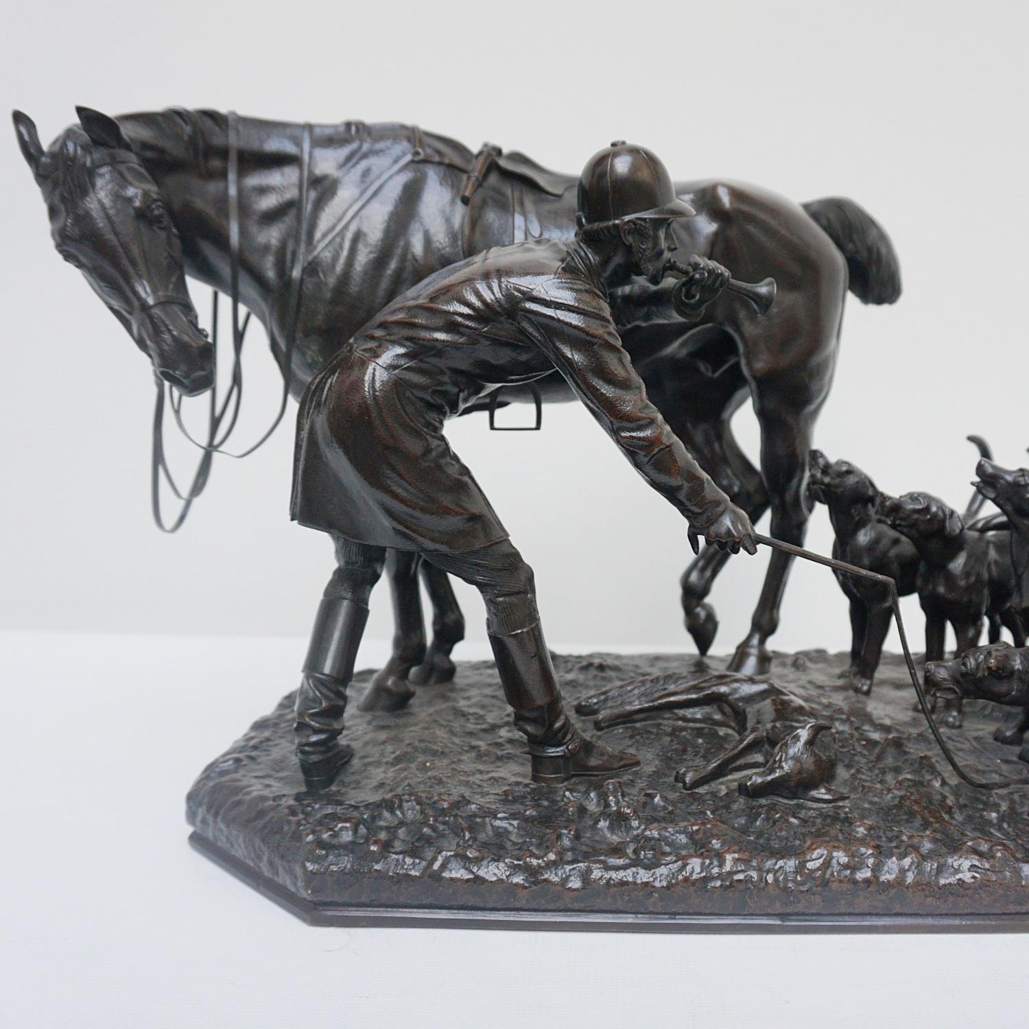 A patinated bronze sculpture by John Willis Good (1845-1878) depicting an English countryside Fox hunting scene. A saddled horse dutifully standing astride his master, whip in hand, whilst the hounds gather around the captured Fox. Set over a