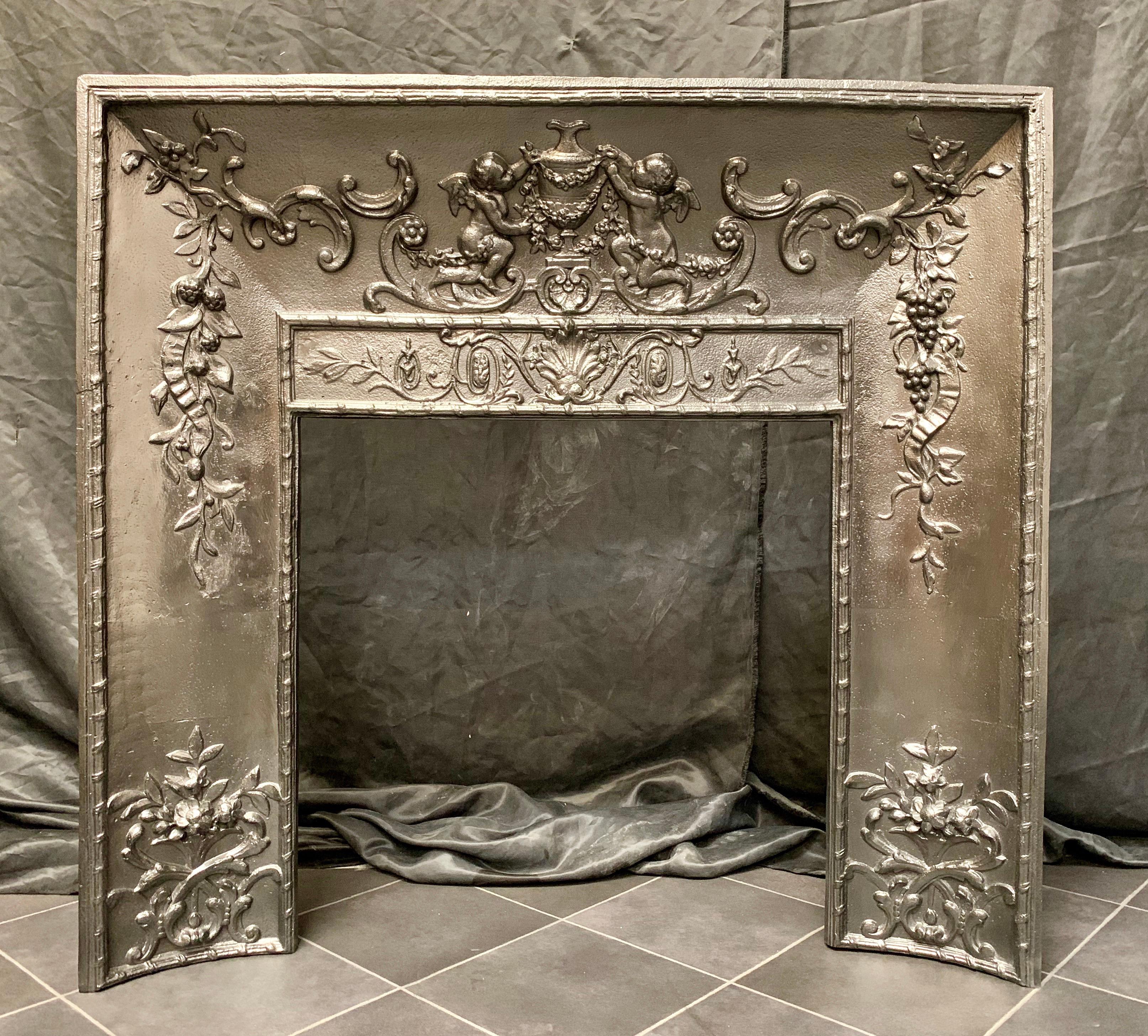 A mid-19th century French cast iron foliate fireplace insert with a centralised urn and swags flanked by a pair of putti.
Inside fire opening size: 575mm wide x 573mm high
Overall insert sizes: 958mm wide x 905mm high x 110mm depth.

French,