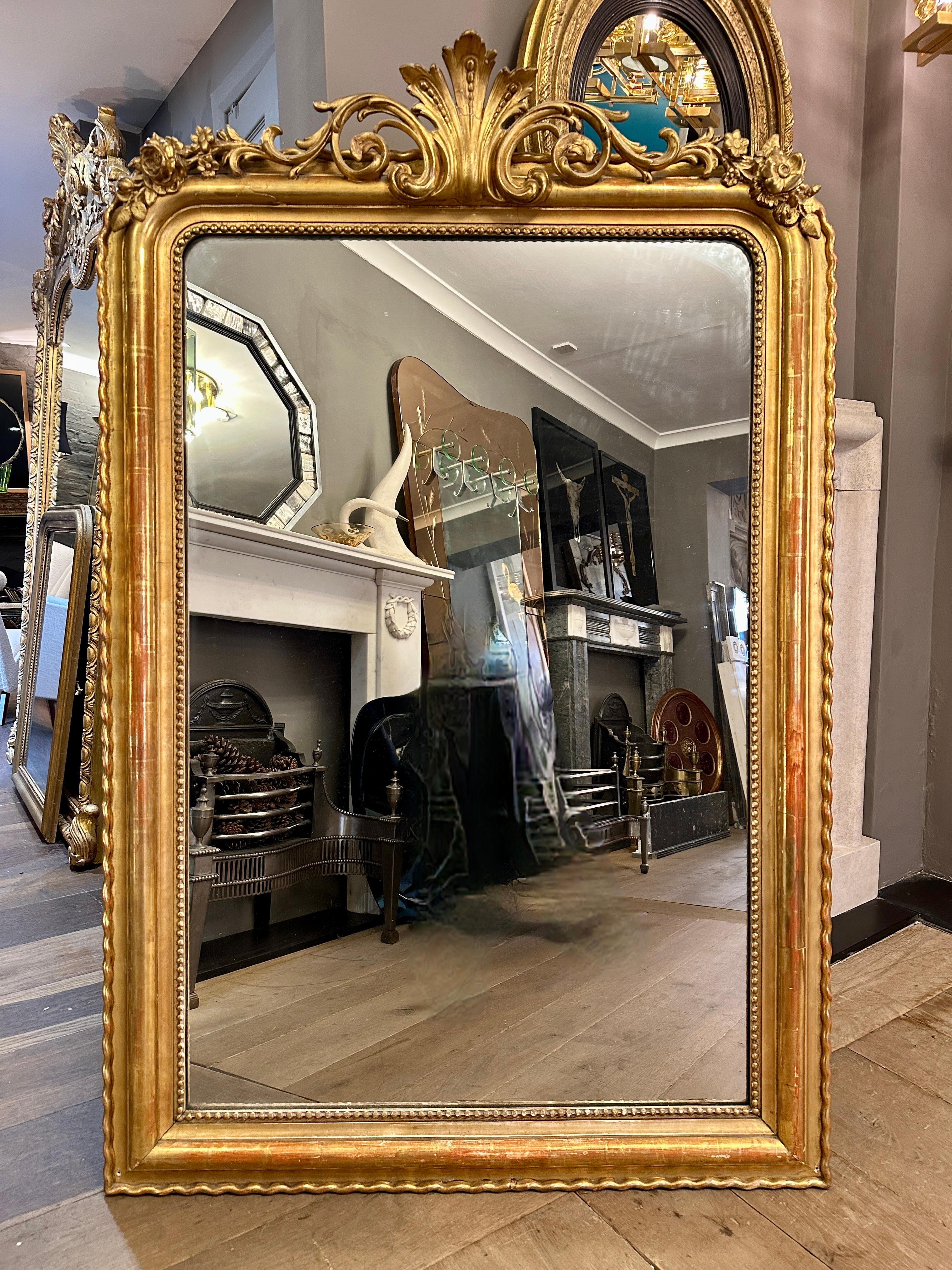 A very good quality French gilt mirror from the mid 19th century Louis Philippe period, with original mercury glass plate. The cartouche pediment reaching across from shoulder to shoulder of the frame with stiff acanthus, scrolls, foliate and