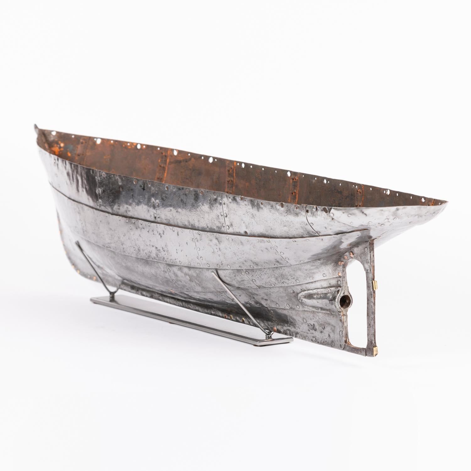 A mid 19th century riveted steel plate hull of a model steam yacht.

Mounted on a later display stand.