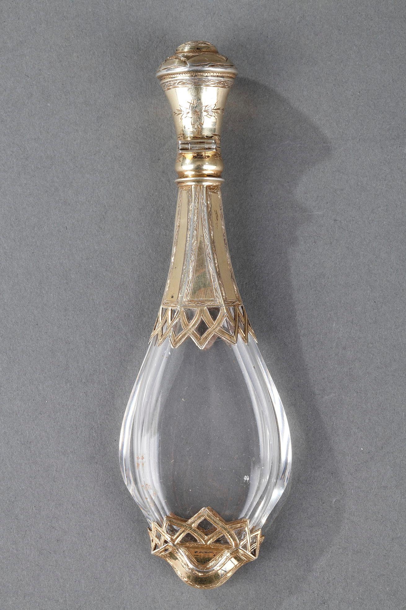 A silver mounted glass scent bottle with shaped baluster body, the part open work collar and foot are pierced and engraved. The circular lid has a stand-away hinge and glass stopper.

H:4.72in. (12 cm) / L: 1.49in. (3,8 cm) / l: 0.66in. (1,7