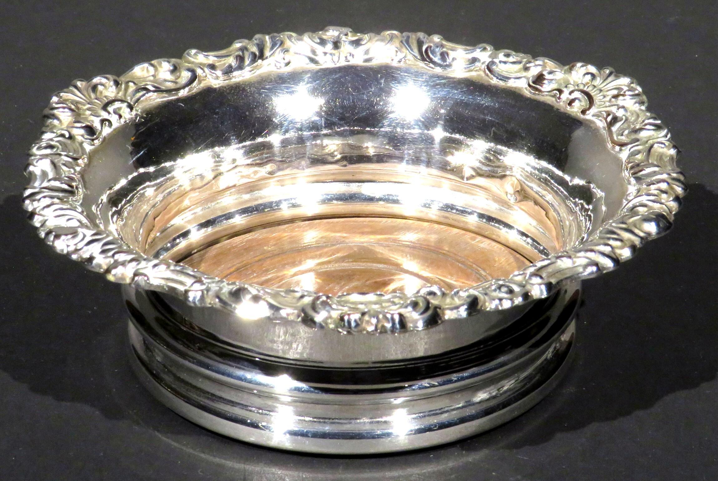 A very good silver plated spirit decanter coaster featuring a high walled body & flaring rim rising from a turned wooden base, the underside lined in red baize. This particular style of coaster was specifically designed to shield spirits such as