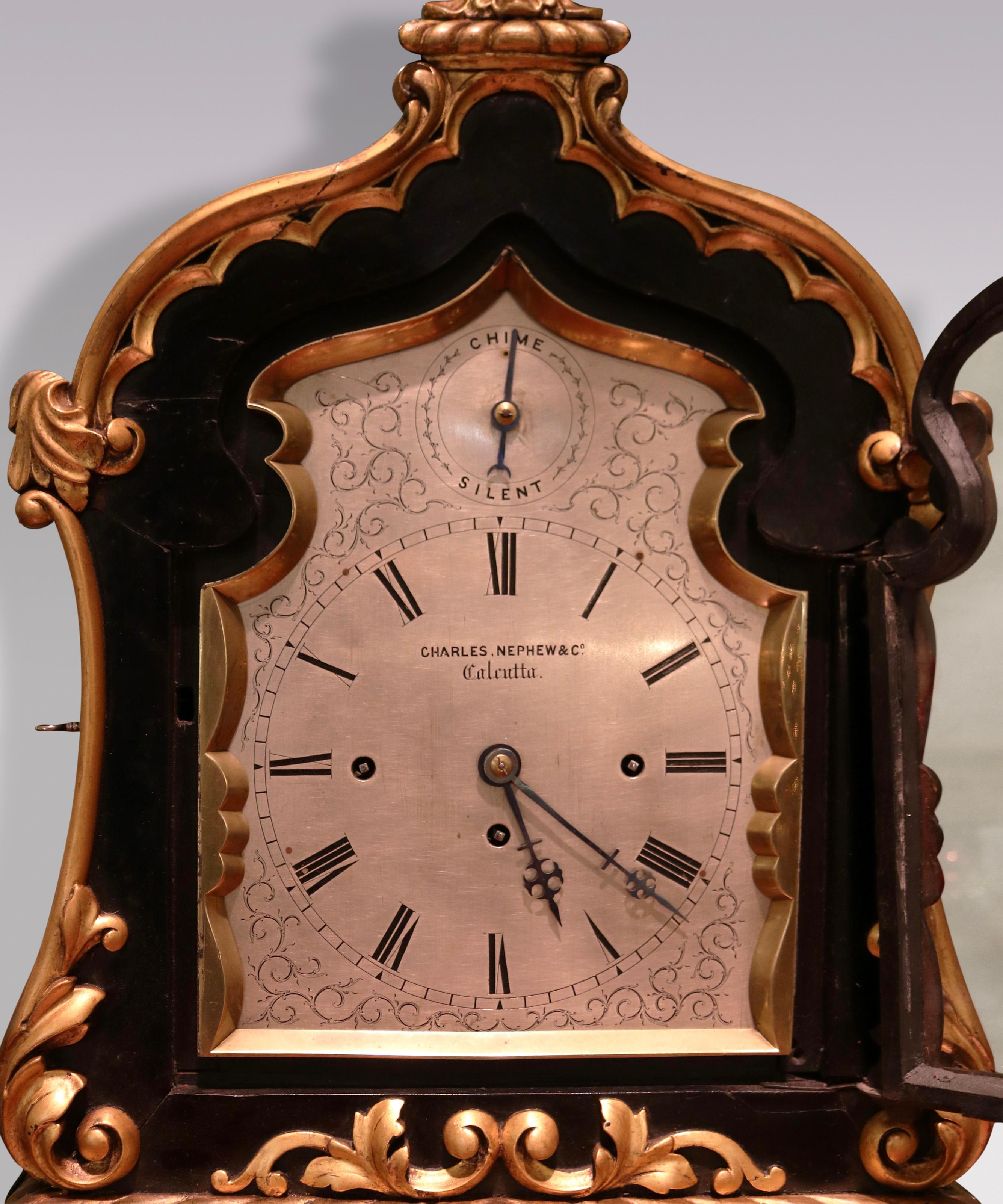 A rare mid 19th Century Bracket Clock of unusual large proportions, the silvered dial 8-day quarter repeat movement striking on bells and gong, by Charles. Nephew & Co, Calcutta.  The Clock housed in ebonised and acanthus carved giltwood ‘Indian