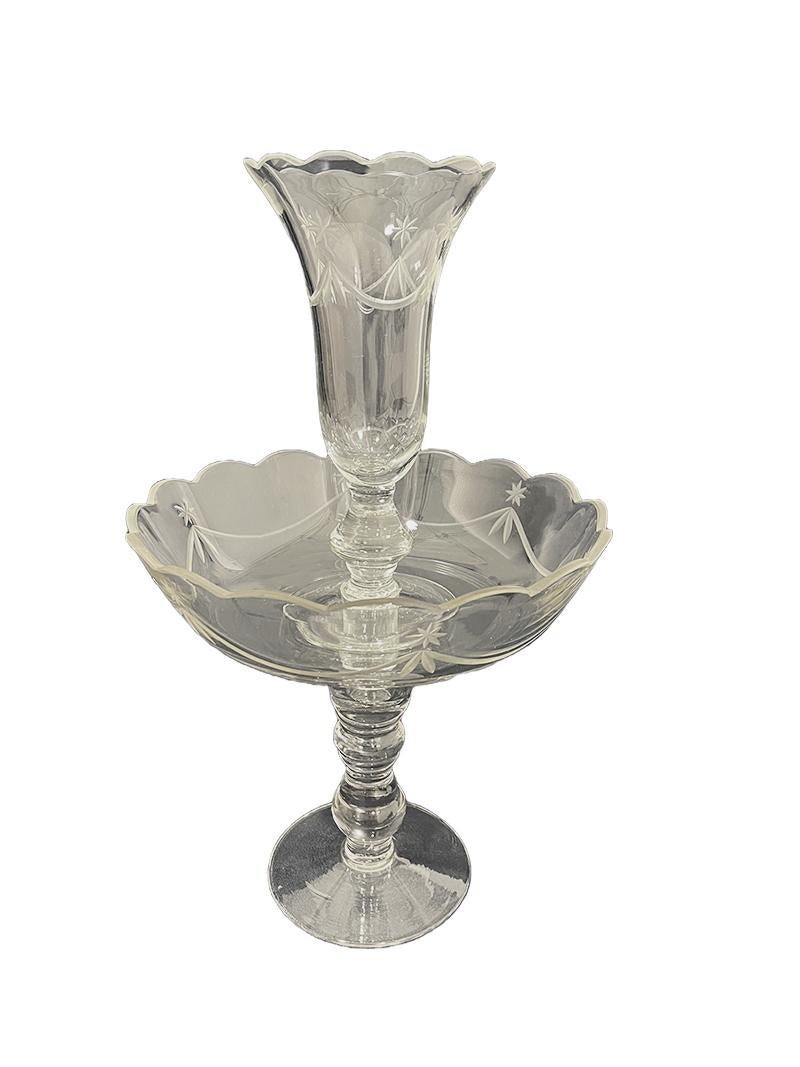A Mid-20th Century crystal footed bowl epergne, flower vase

A crystal epergne with etched scene of a star above a garland. This set consists of 2 parts crystal. A footed bowl, raised on a knobbed foot and a fluted vase which can be placed in the