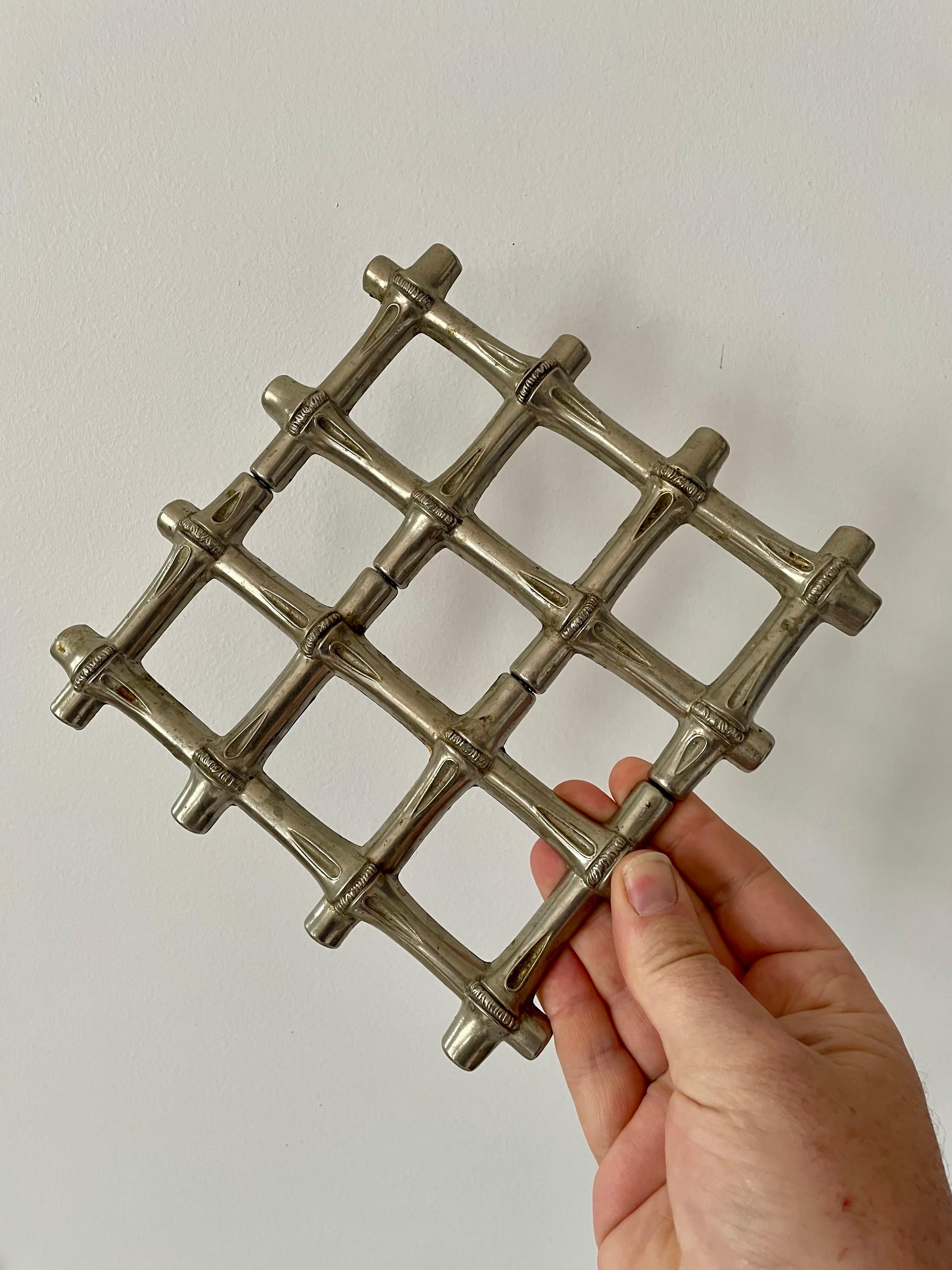 A stylish and functional Italian trivet in a faux bamboo design, both elegant and practical. This telescopic piece easily expands from 18.5 cm (7.3 in) to 24.5 cm (9.6 in), making it ideal for accommodating larger serving dishes or platters. Its