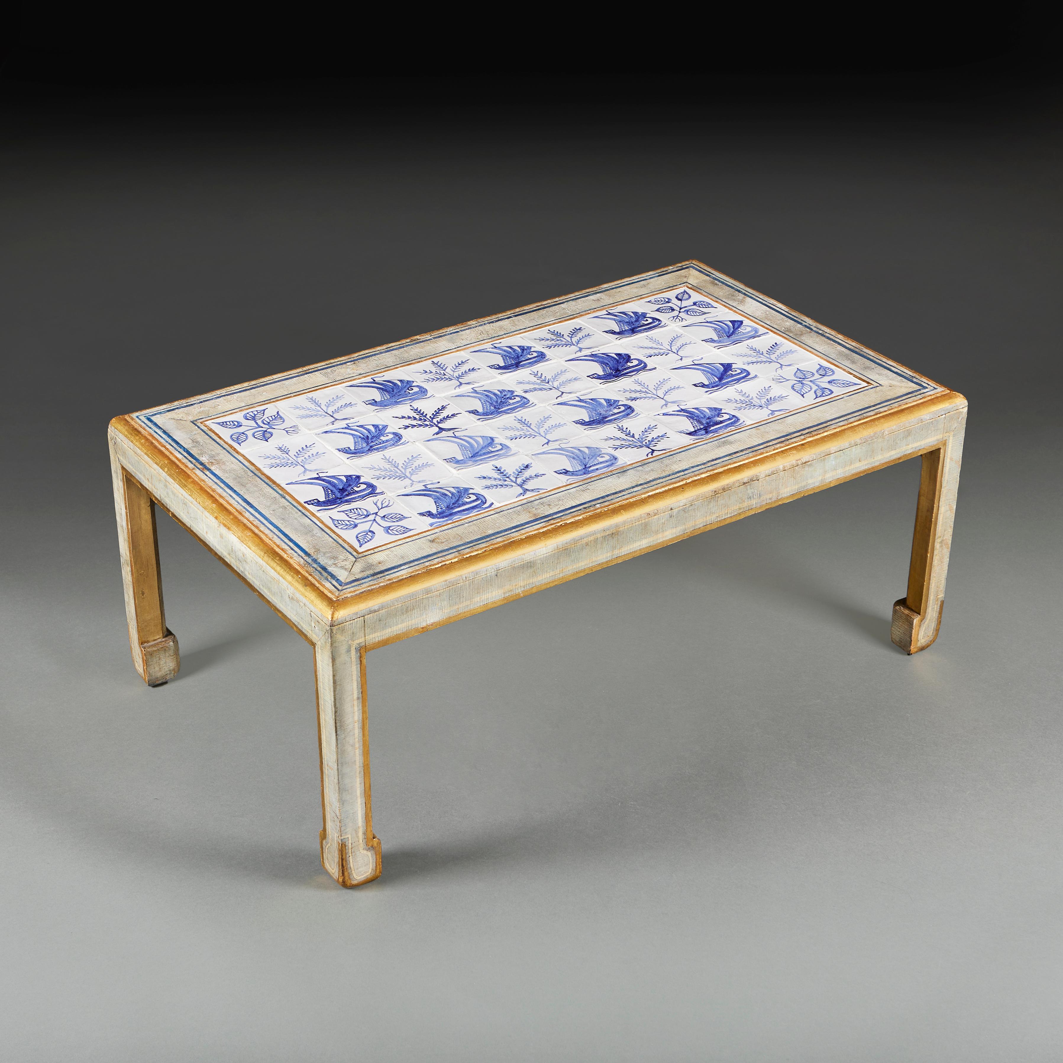 A midcentury low table decorated with 32 blue and white Delft tiles, mounted in a craquelure decorated wooden frame with Cobham leg. By Mallett of New Bond Street, London.