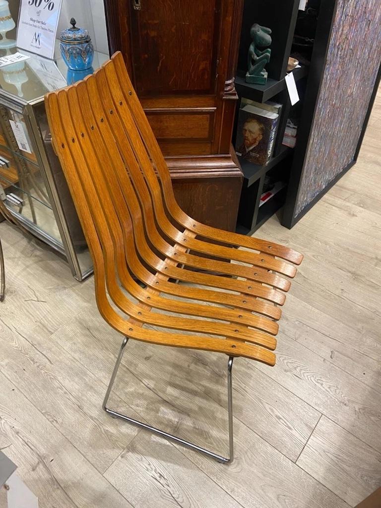 An original vintage Teak Scandia Senior chair, designed in 1957 by acclaimed Norwegian designer Hans Brattrud for Hove Møbler.

These iconic chairs feature gently curved backs formed from laminated wood slats, offering a sleek, sculptural profile.