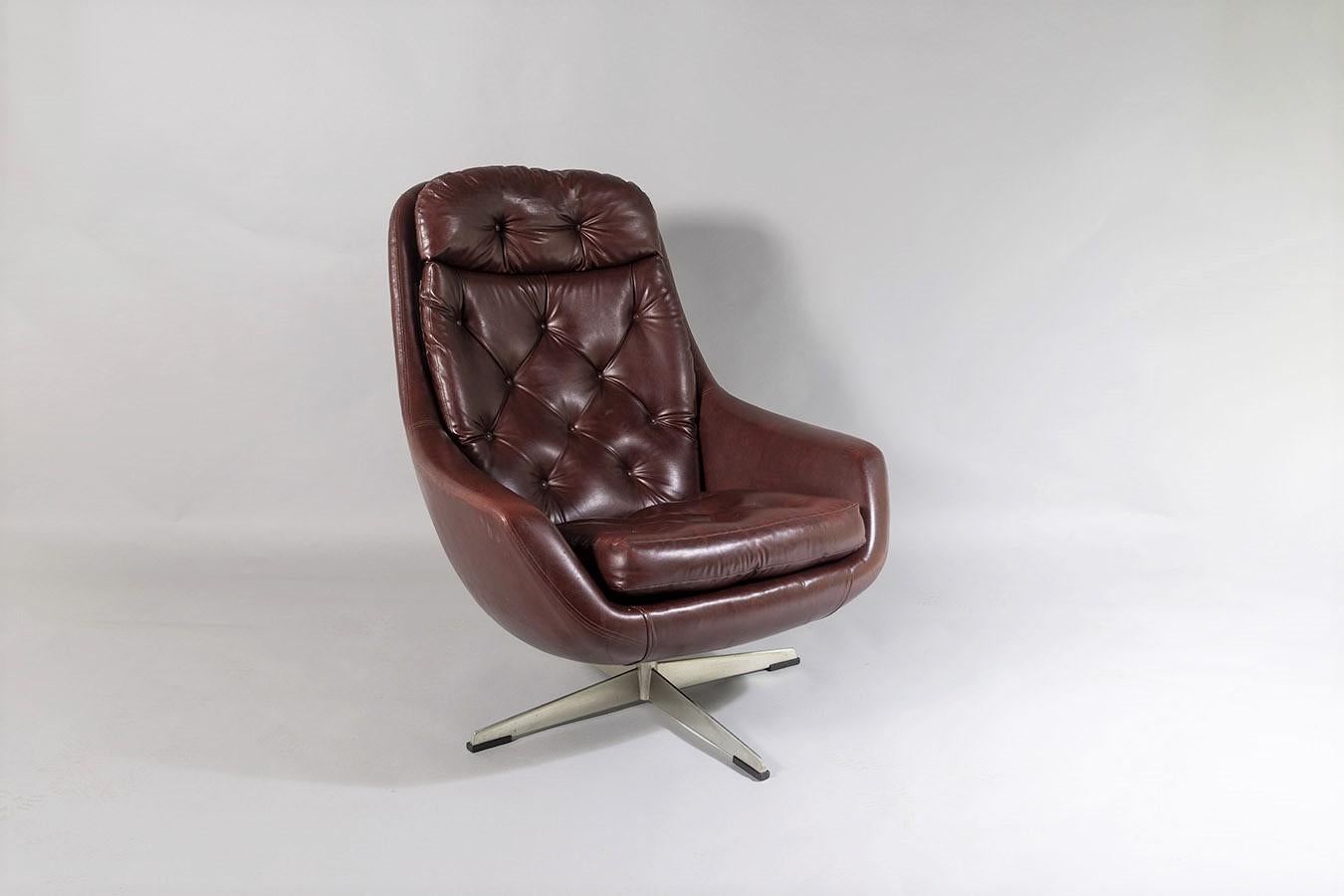 A mid century 1960s swivel egg armchair in a dark reddish brown faux leather.
Button back removable seat and backrest cushion in very good original condition.  The chair sits on a satin chrome metal base which still retains all four black nylon