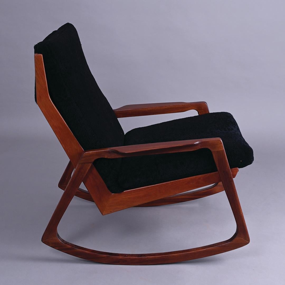 A midcentury 1960s Afromosia framed rocking chair. Reupholstered in black leather and black sheepskin.