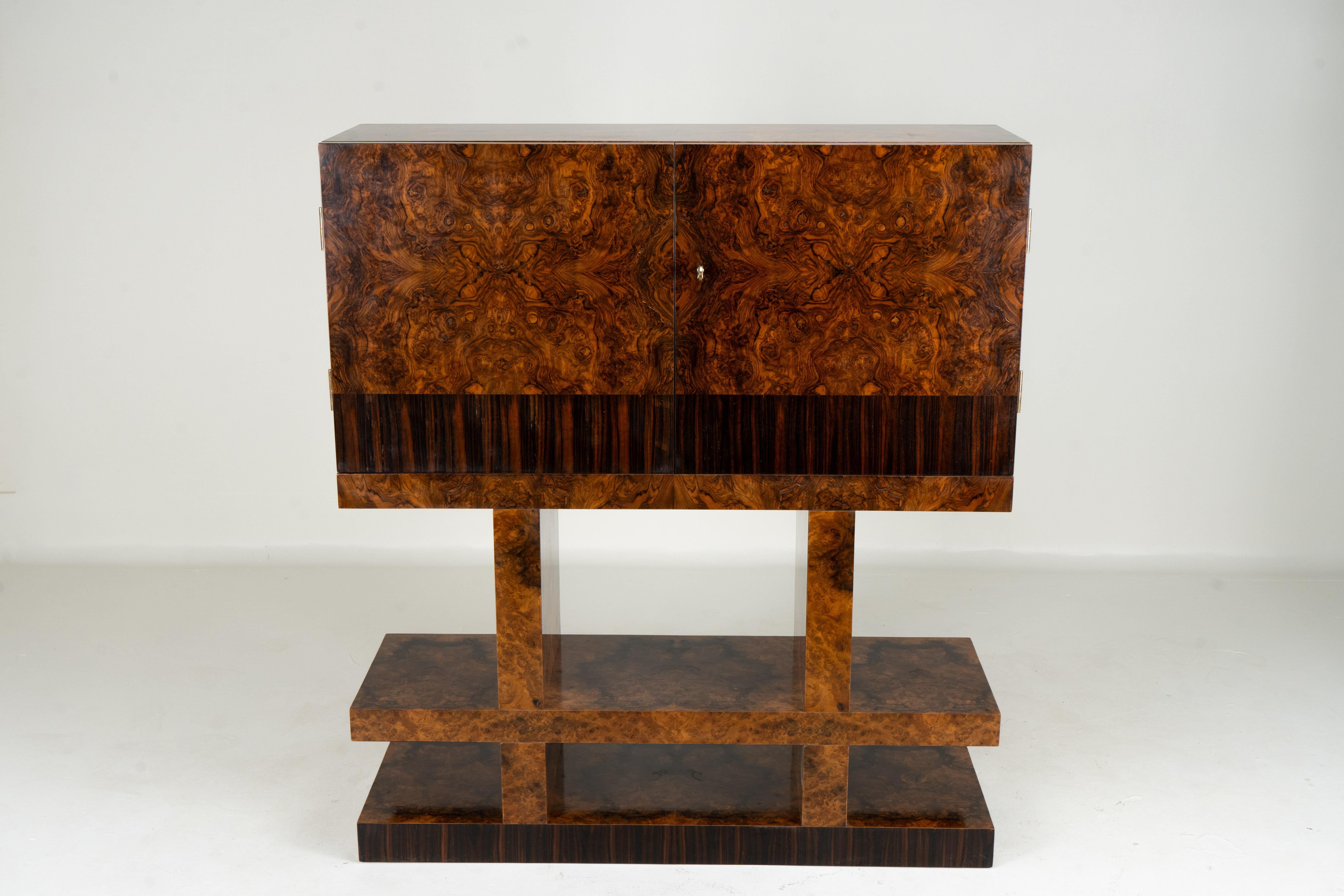 This unique Mid-Century bar cabinet is clad in book-matched walnut burl veneer and has a cubist style.   The finish is silky-smooth French polish.  All exterior surfaces have a rich nut-brown color.  Turning the solid brass key to open the doors,