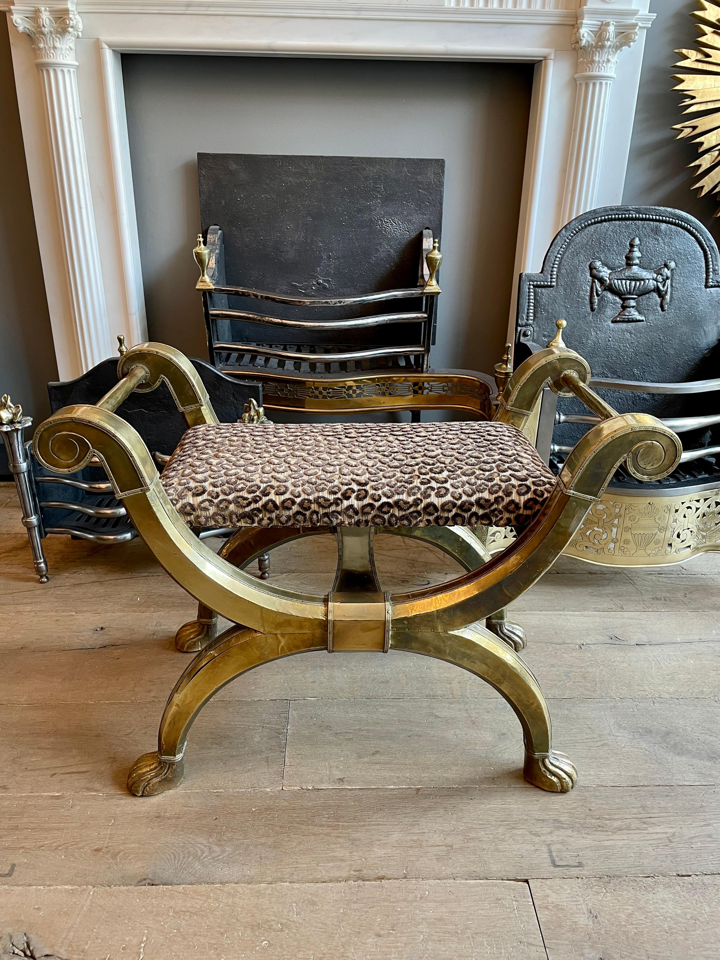A mid to late 20th century stool in the Empire manner, the frame covered in hand worked and stamped brass. The scrolled handled frame terminating in paw feet. The seat reupholstered in cut leopard print fabric. Attributed to Rodolfo Dubarry.