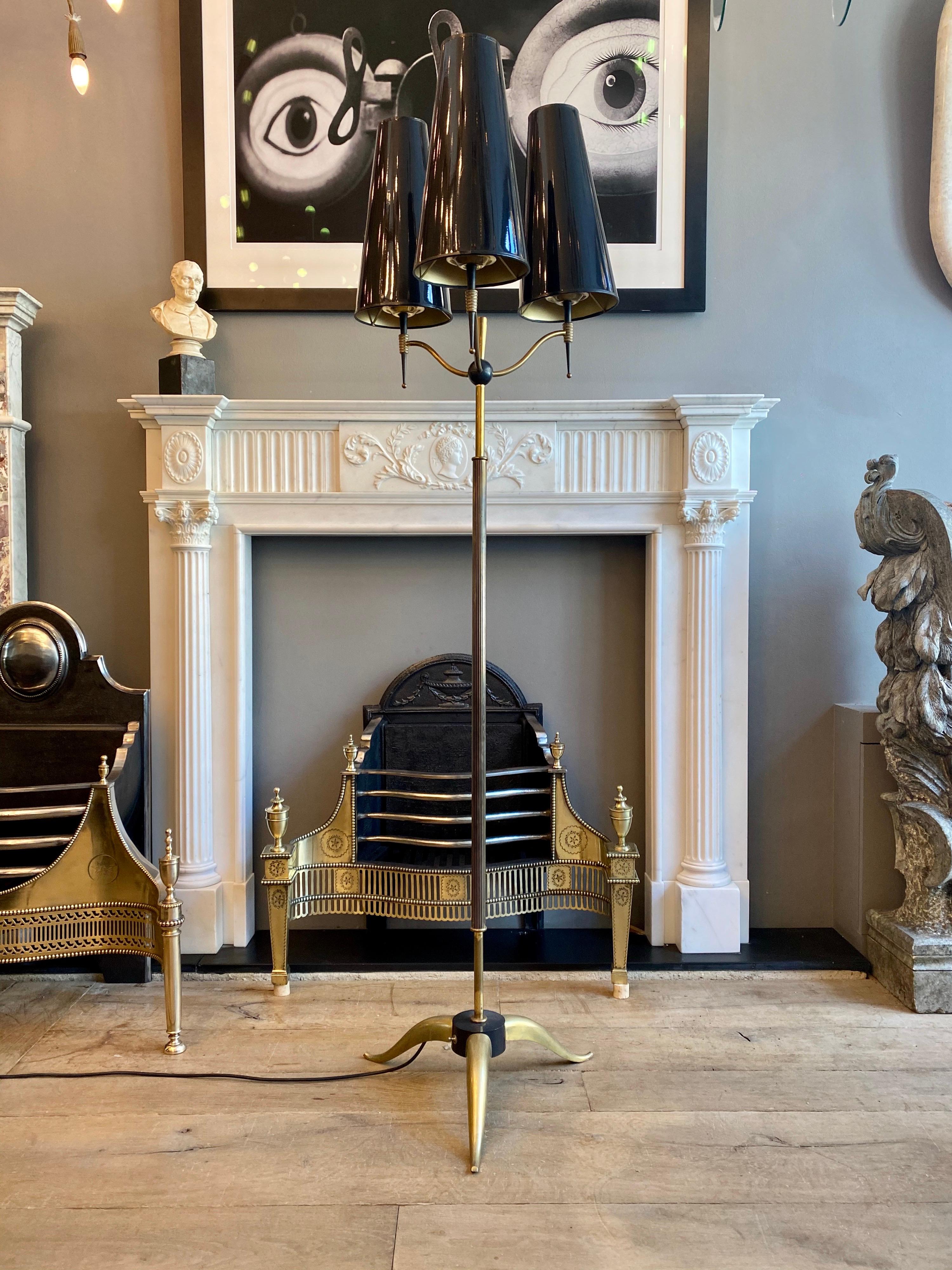 A continental mid-20th century floor lamp in brass with black accents and tall black conical lacquered shades. The tripod foot with switch supporting a reeded stem, surmounted by a black orb with three arms.