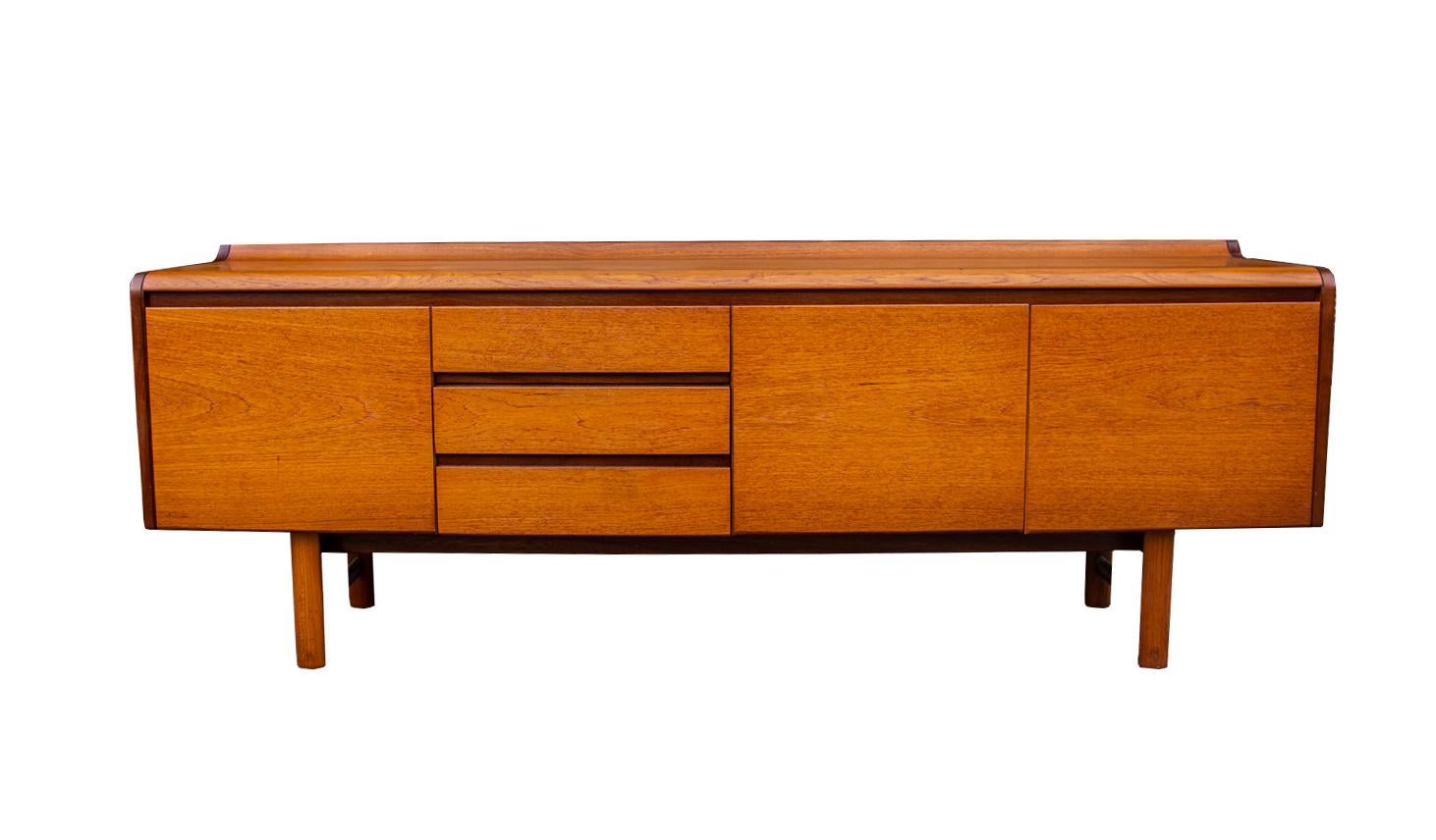 Beautiful joinery in a wonderfully grained and patinated teak. Ideal mellowed cognac colouration. Timeless chic minimal lines and proportions with flush facing doors and drawers. The top back section with a swooping uplift to the form.  Excellent