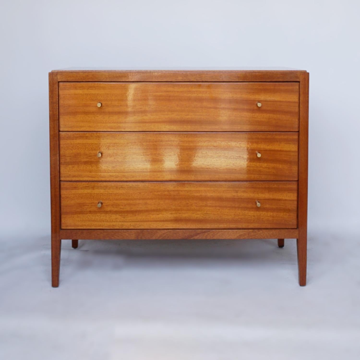 A mid-century low chest of three drawers designed by Neville Ward and Frank Austin for Loughborough Furniture, and retailed by Heal's of London. Figured olive walnut throughout with original metal handles. 

Dimensions: H 72cm, W 84cm, D