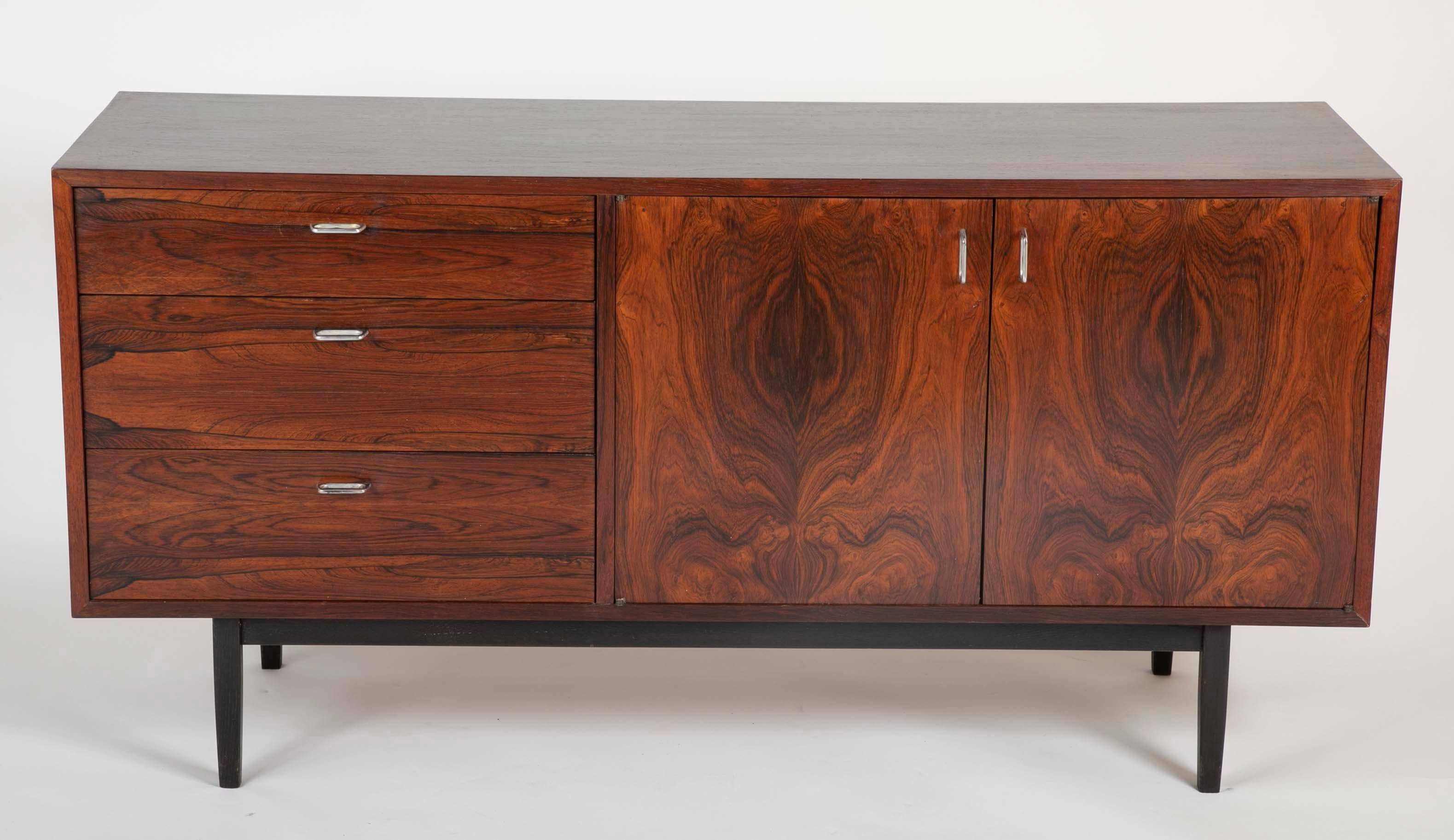 An interesting rosewood sideboard or credenza with ebonized legs and sculptural aluminum handles. Having one two-door compartment and on the other side three draws; the top of which is divided for cutlery. Newly restored.