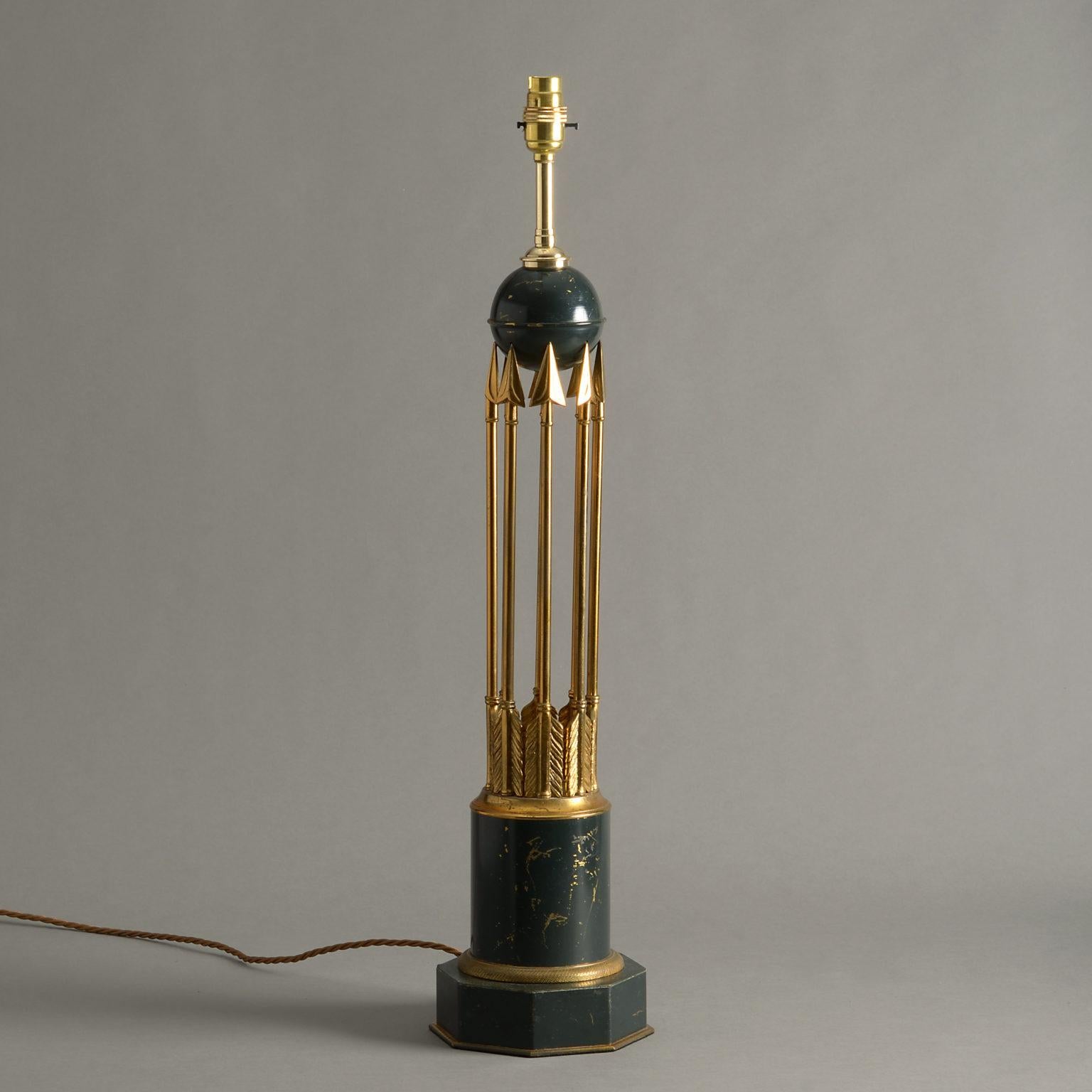 A mid-20th century tole and gilt brass table lamp, the body consisting of a dark green painted sphere, supported by a cluster of arrows, set upon a circular base, having an engine turned brass ring mount upon an octagonal socle.

Dimensions refer