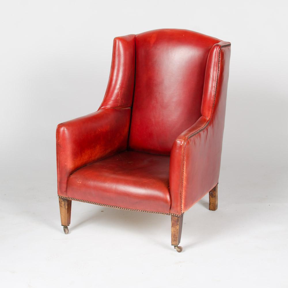 An English red leather club wingback armchair with nail heads details and rolling casters circa 1960.