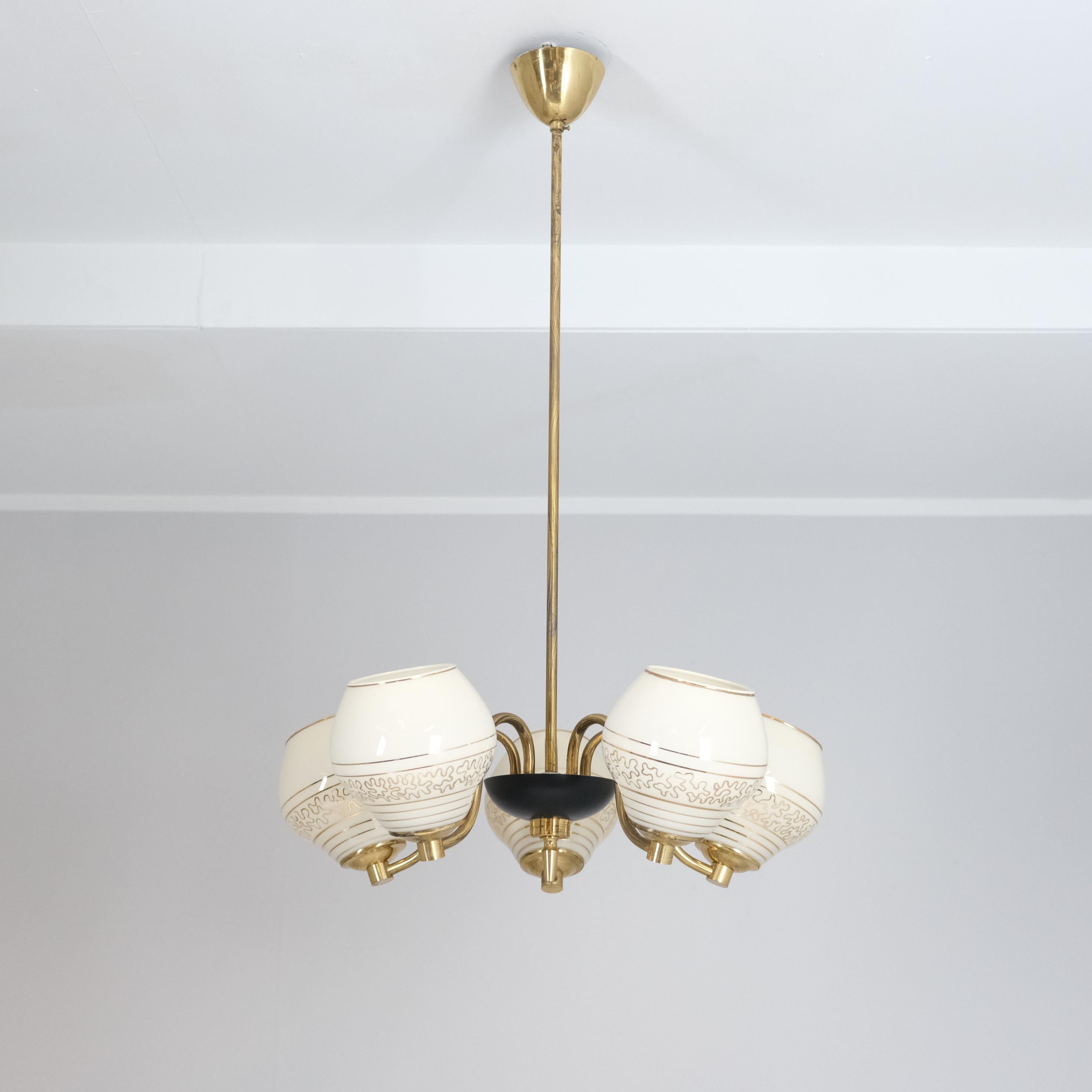 Preciosa lámpara de techo de cinco brazos fabricada por Saariston Valaisin a finales de los años 50 o principios de los 60, con tulipas de cristal pintadas a mano y una elegante estructura de latón. Esta lámpara capta el lado cálido y decorativo del