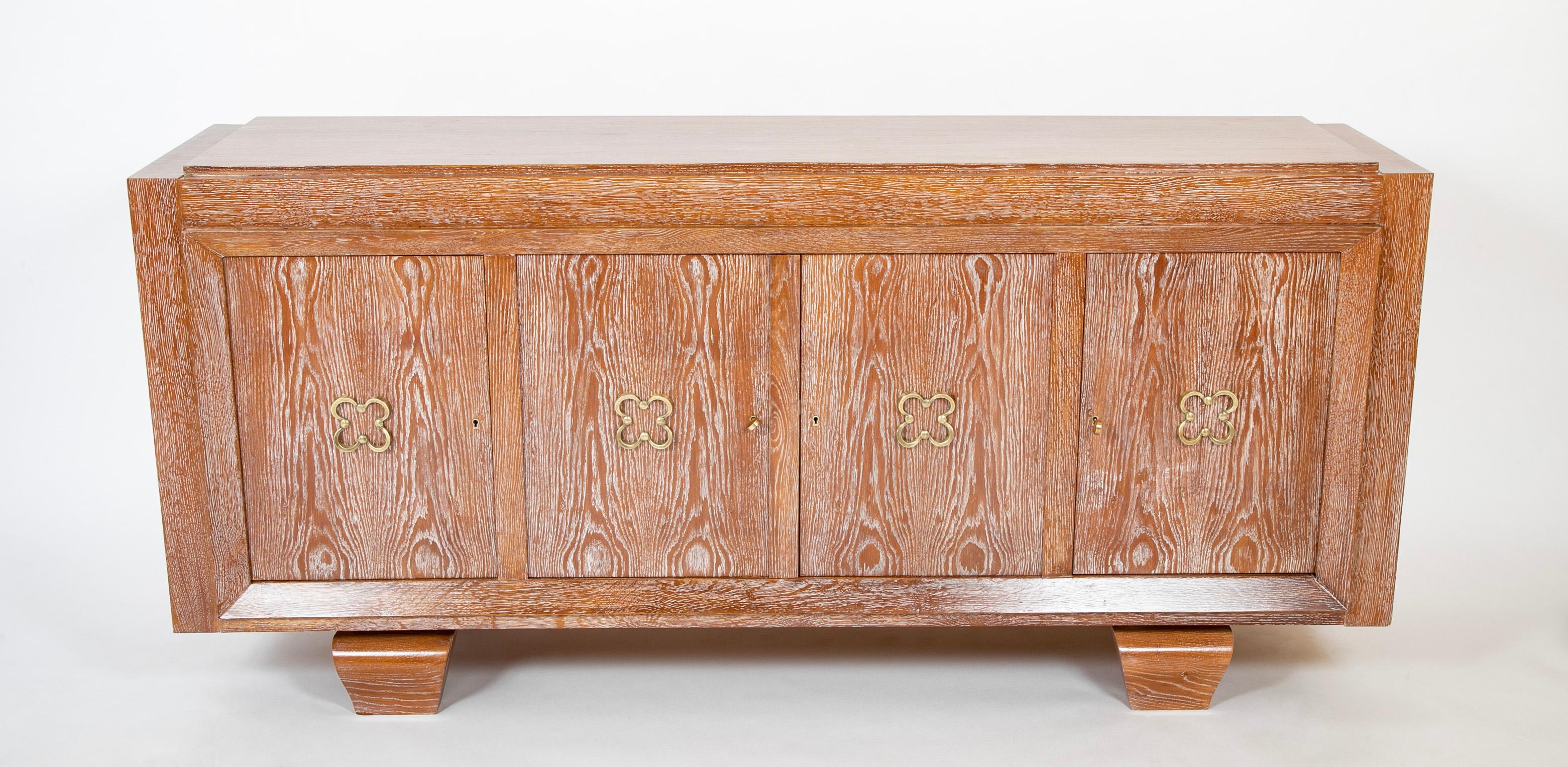 A Mid-Century French cerused oak sideboard having four doors opening to shelves and drawers with Four Leaf Clover handles in the manner of Jean Royere.   Circa 1940.