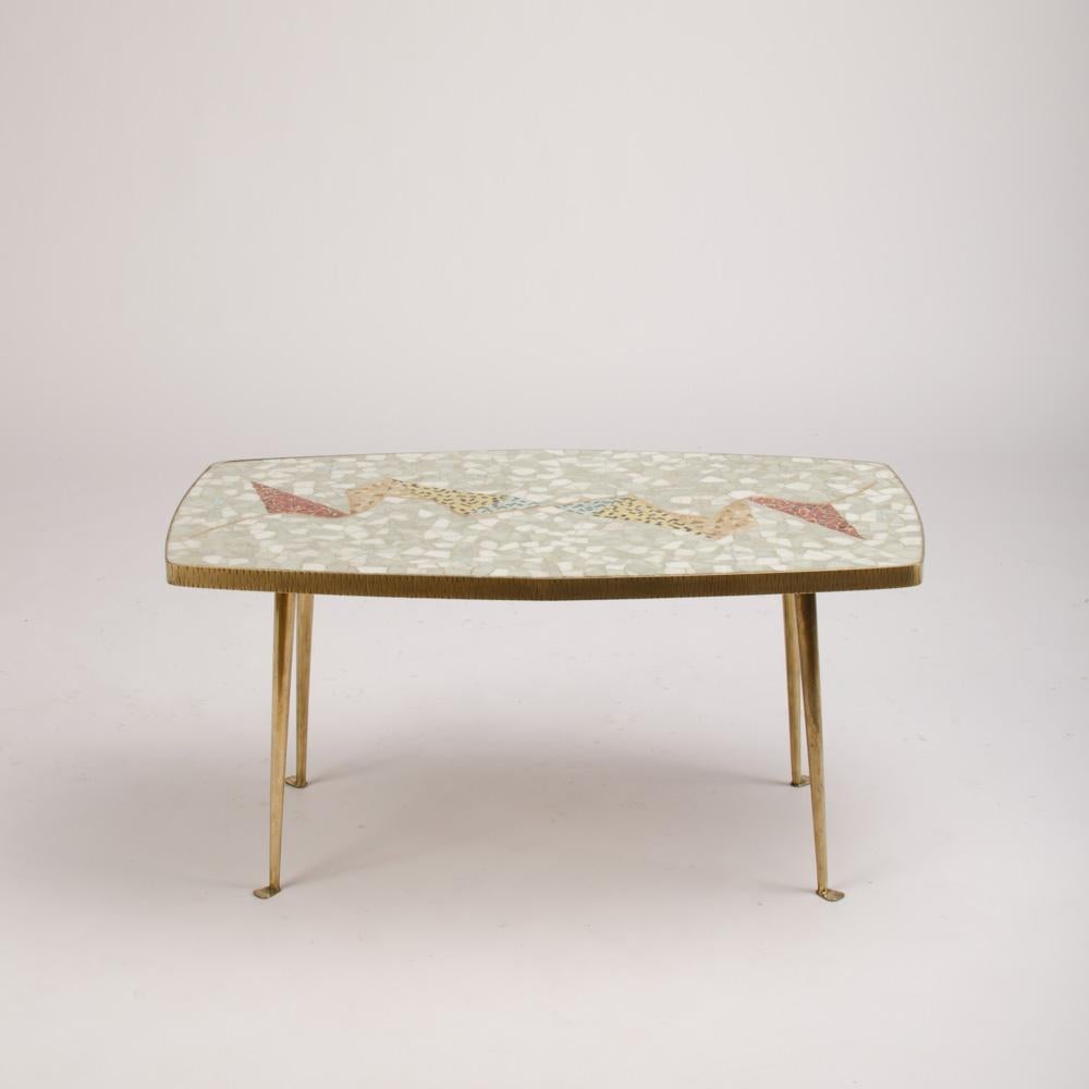A German mid-century mosaic coffee table C 195
 0. The table has a interesting double Trapeze form. The edging of the tabletop is made of metal as well as the tapered legs. Cream and pastel mosaic tiles.