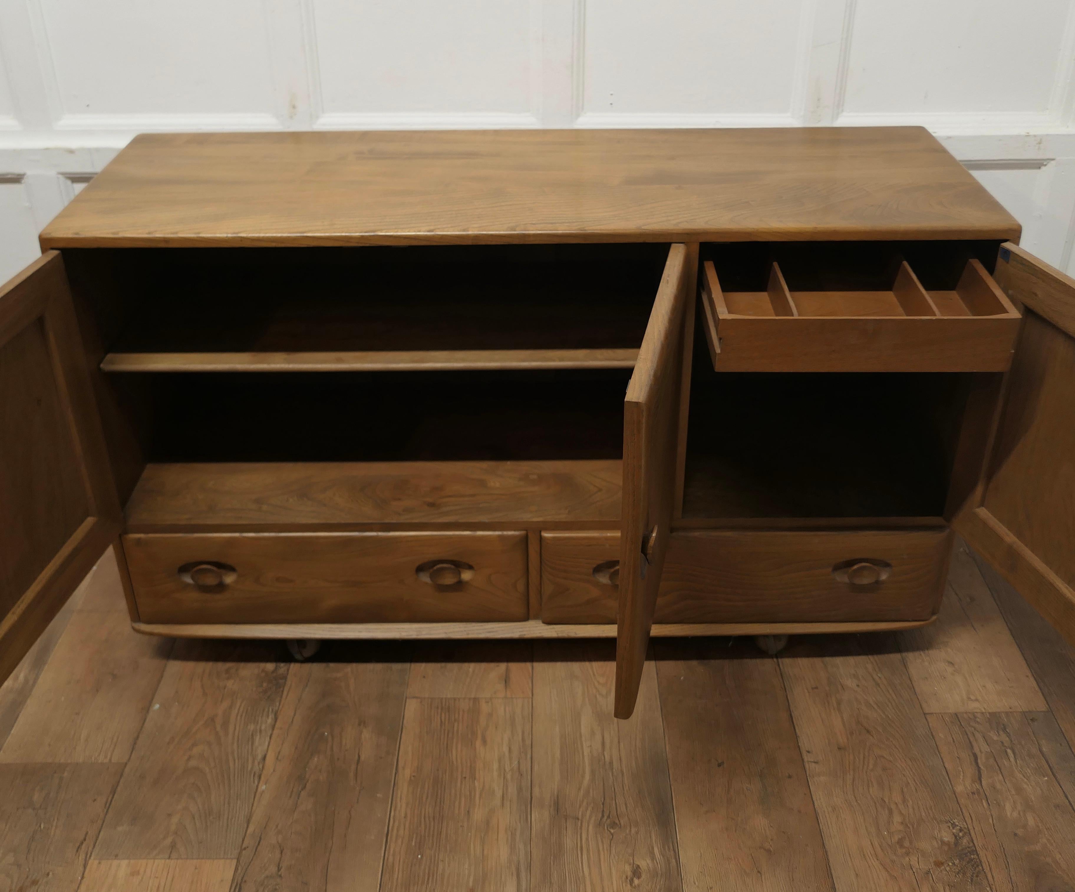 A Mid Century Golden Elm Sideboard by Ercol  The sideboard has 3 cupboard doors  1