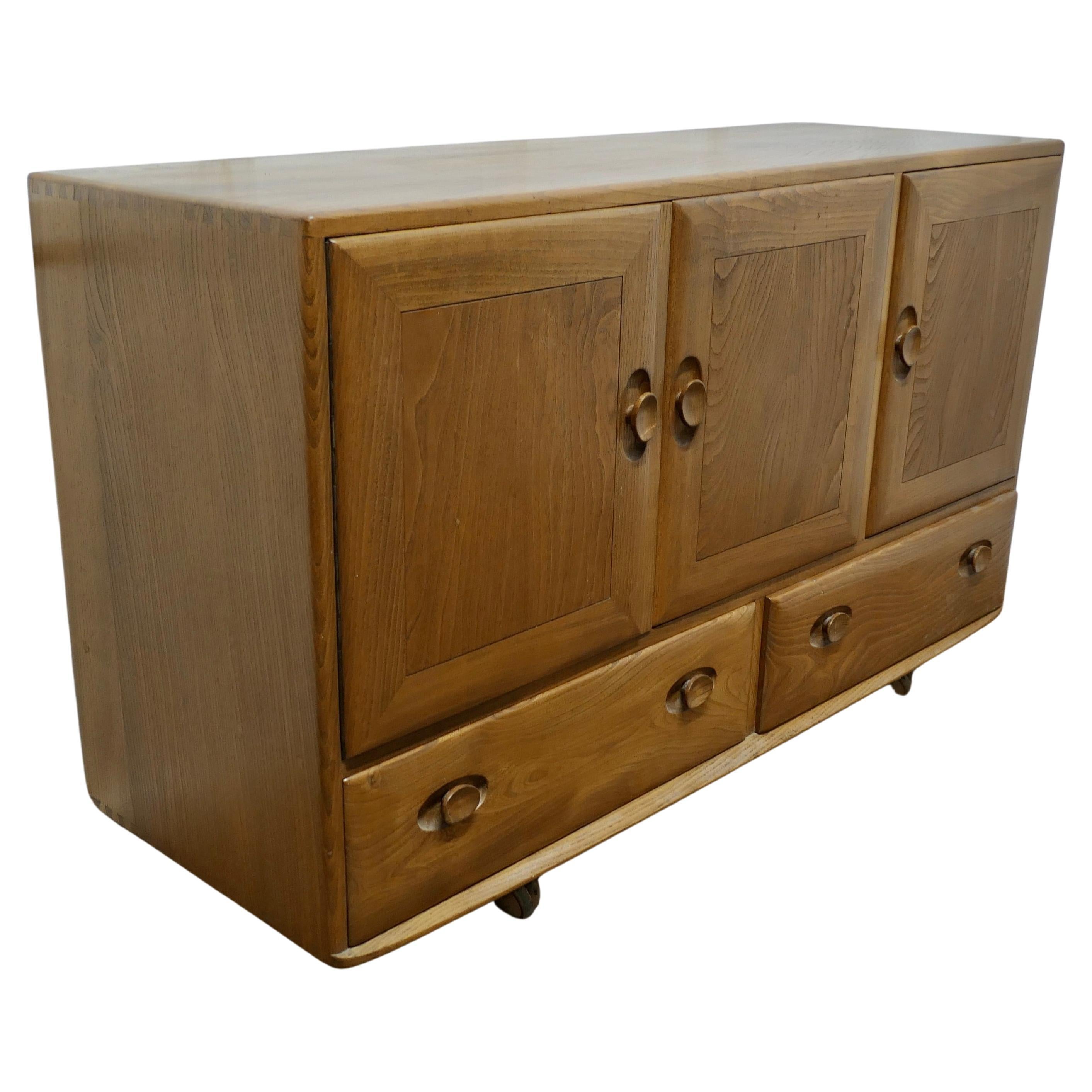 A Mid Century Golden Elm Sideboard by Ercol  The sideboard has 3 cupboard doors 