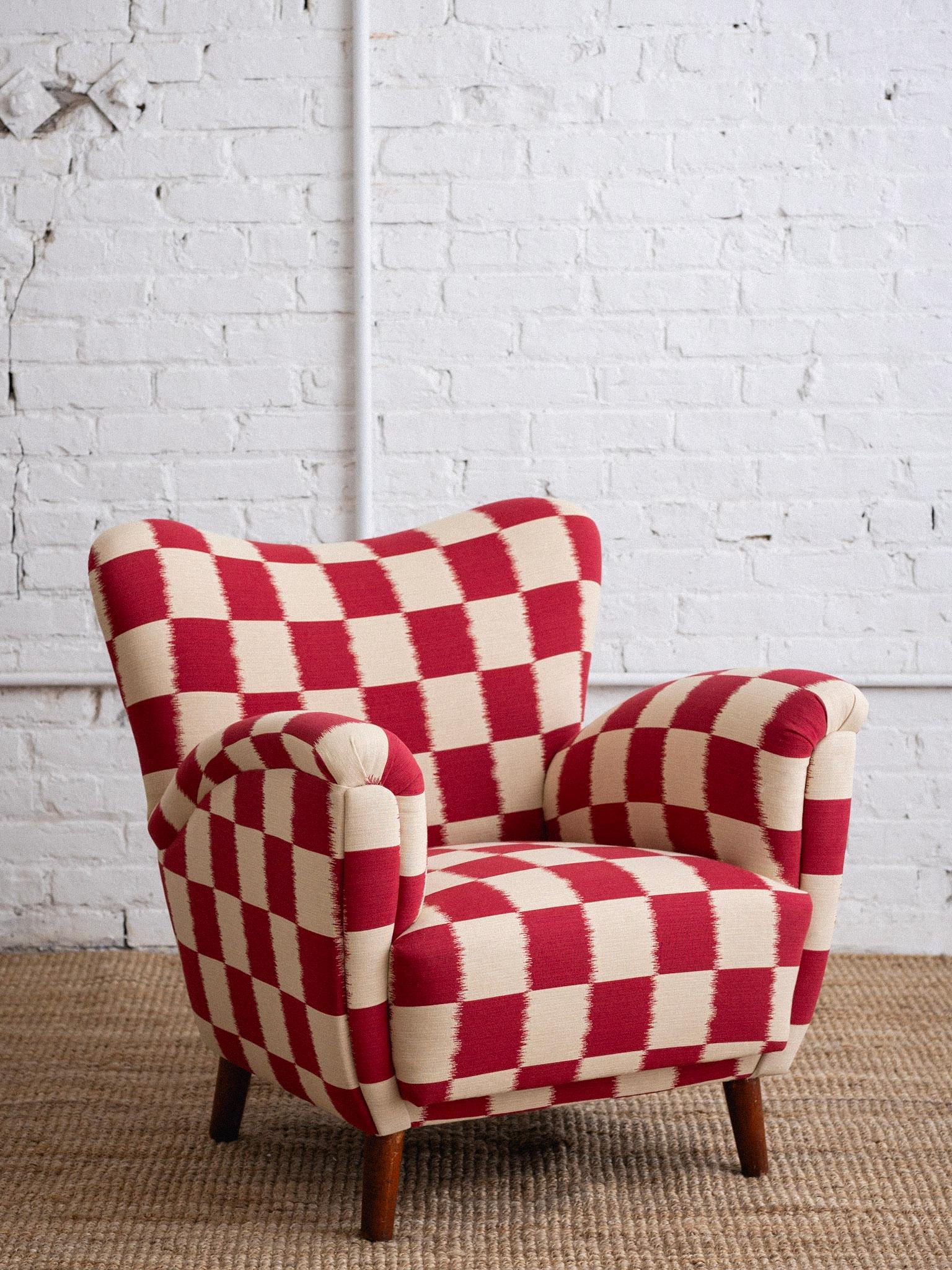 A mid century Italian chair. Low profile and wingback style silhouette. Newly reupholstered in a red and cream ikat checkered jacquard. Sourced outside of Florence, Italy. Matching sofa also available, sold separately.