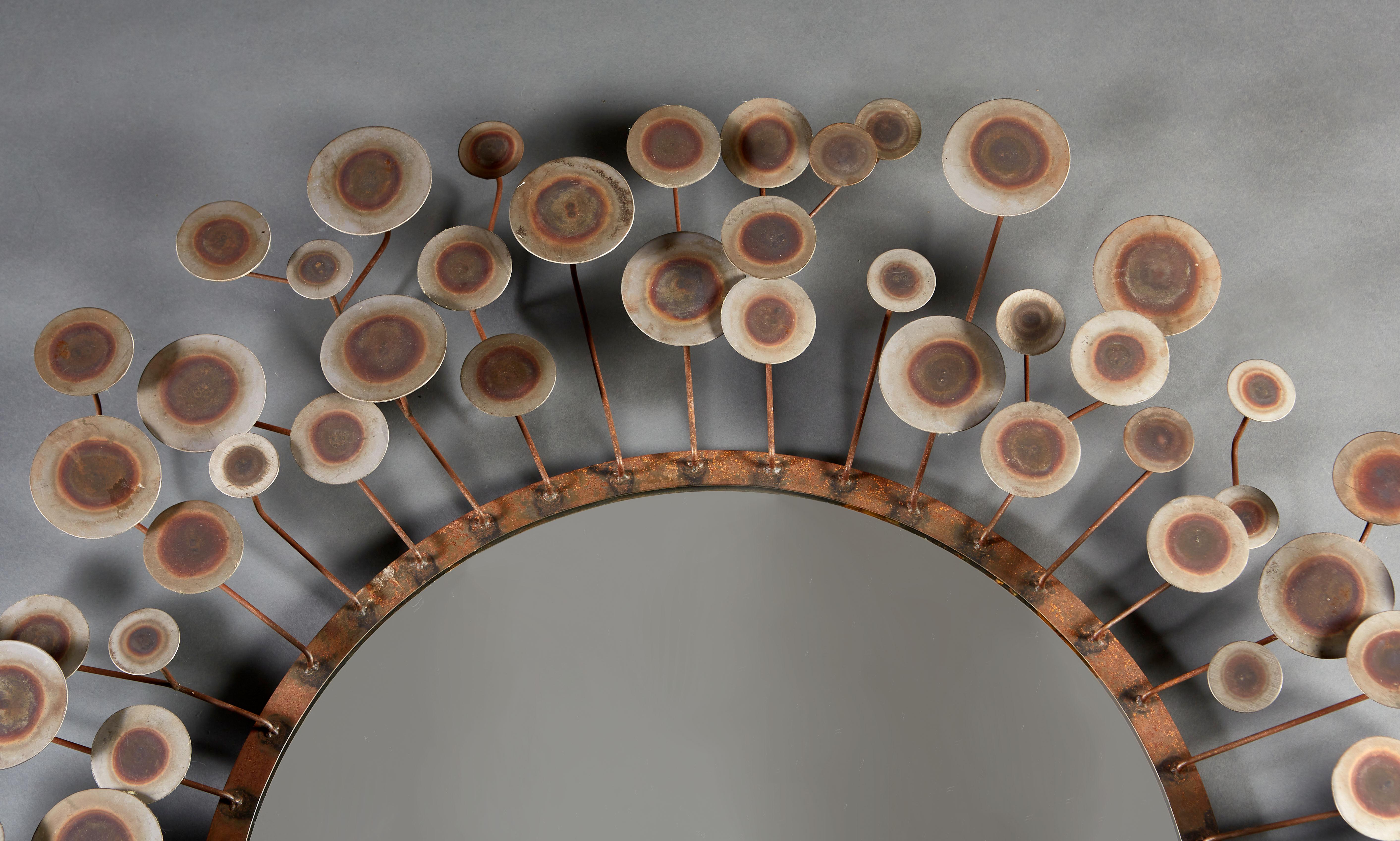 An unusual mid-century Italian mirror of circular sunburst form, with multi layered arms terminating in patinated steel discs.