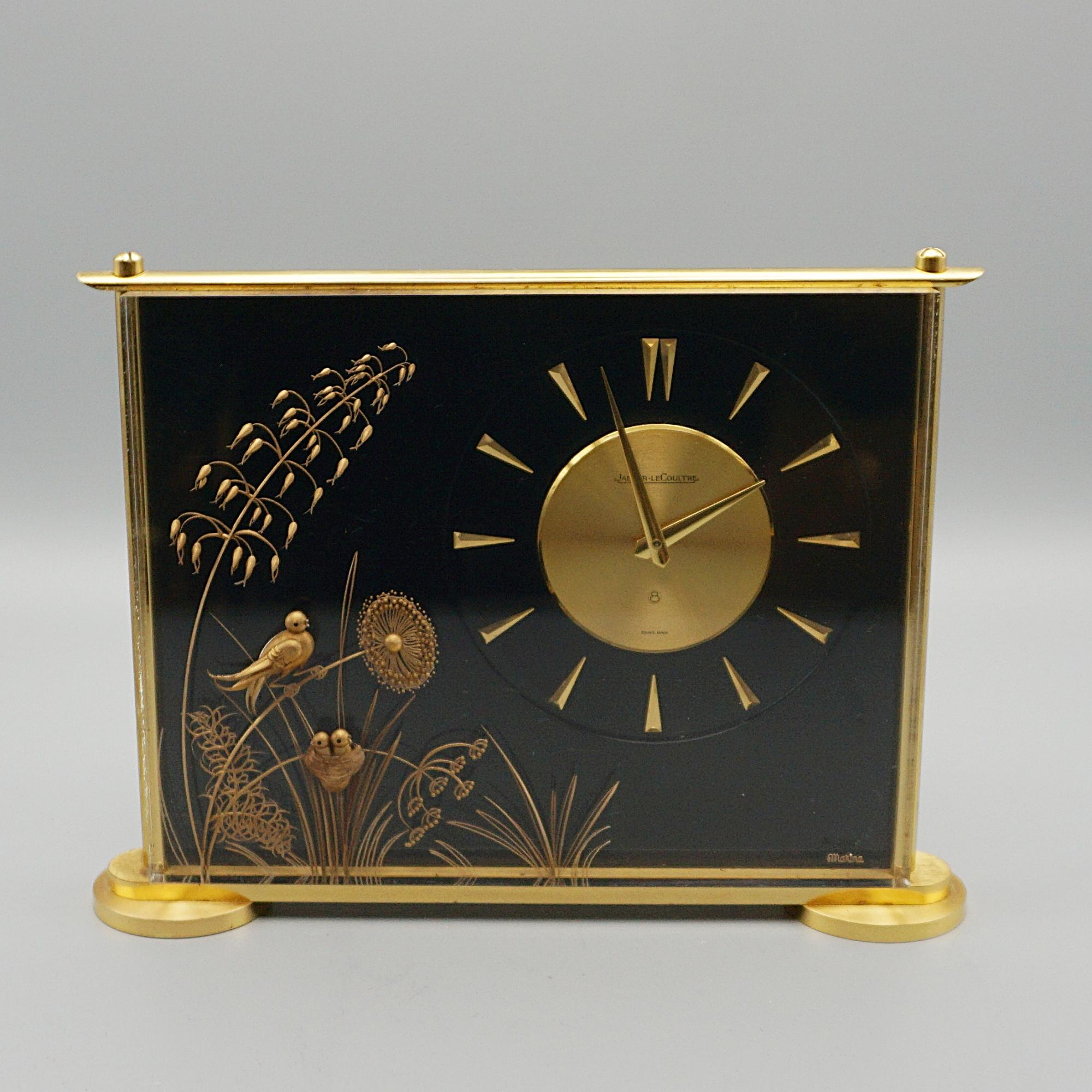 A Mid-Century Jaeger-LeCoultre mantel clock in a Lucite case. Inset brass decoration featuring wadding birds amongst foliage. Set over a gilded Brass stepped base. Eight day movement by Jaeger-LeCoultre with baton numerals and original gilded hands.