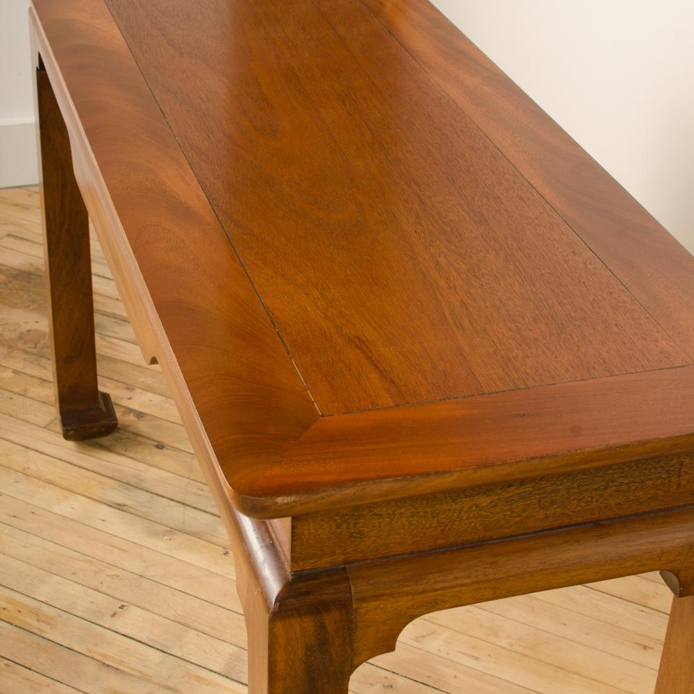 A beautiful midcentury mahogany console in the manner of James Mont, circa 1950. The table has a large beveled edge and Ming horseshoe feet.