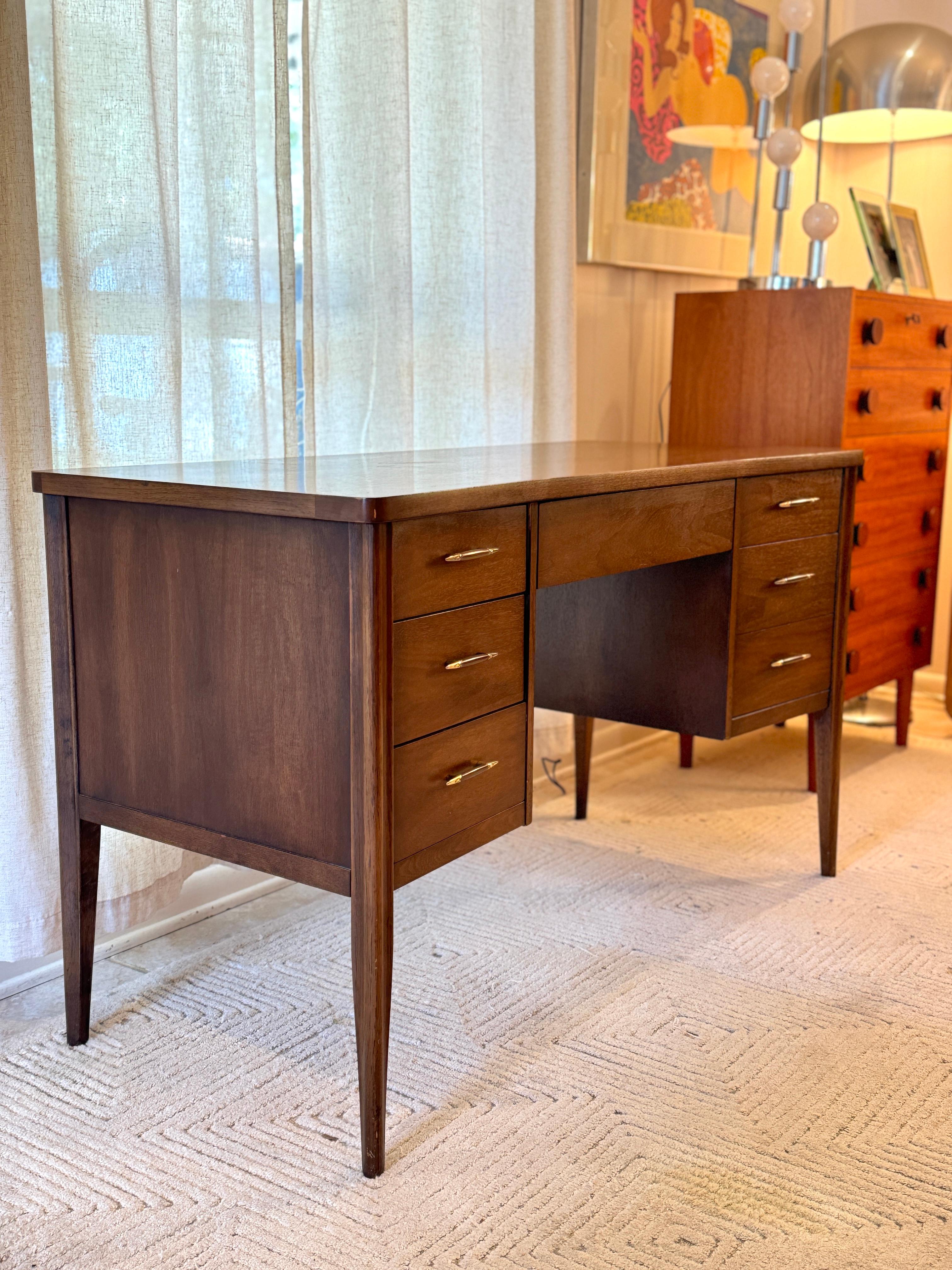 A mid century modern American icon, the Saga desk by Broyhill. One of the most inspired collections form the era. Subtle design details, elongated ellipse metal pulls, tapered legs, slight bow-tie angle to the front edge of the desk. Lots of storage