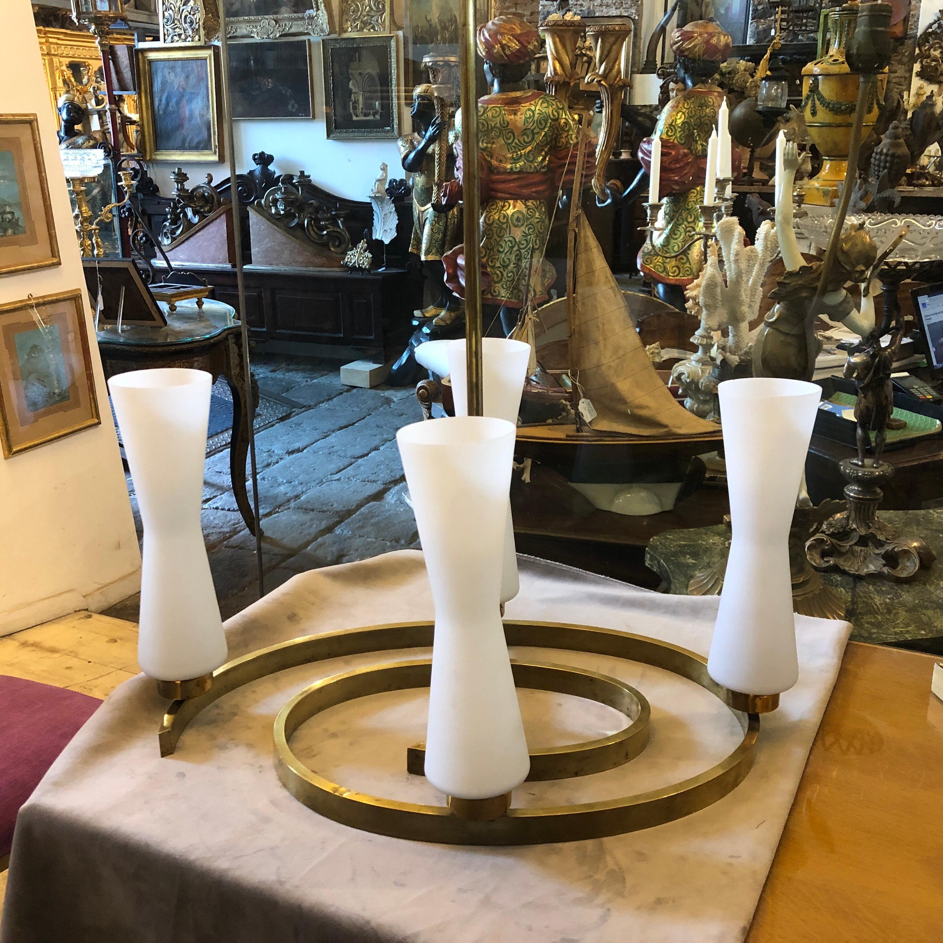 Un raro lampadario progettato e prodotto in Italia negli anni '50, i diffusori in vetro opalino bianco sono in perfette condizioni, l'ottone massiccio è in patina originale che gli conferisce un vibrante aspetto vintage. Funziona sia a 110 che a 240