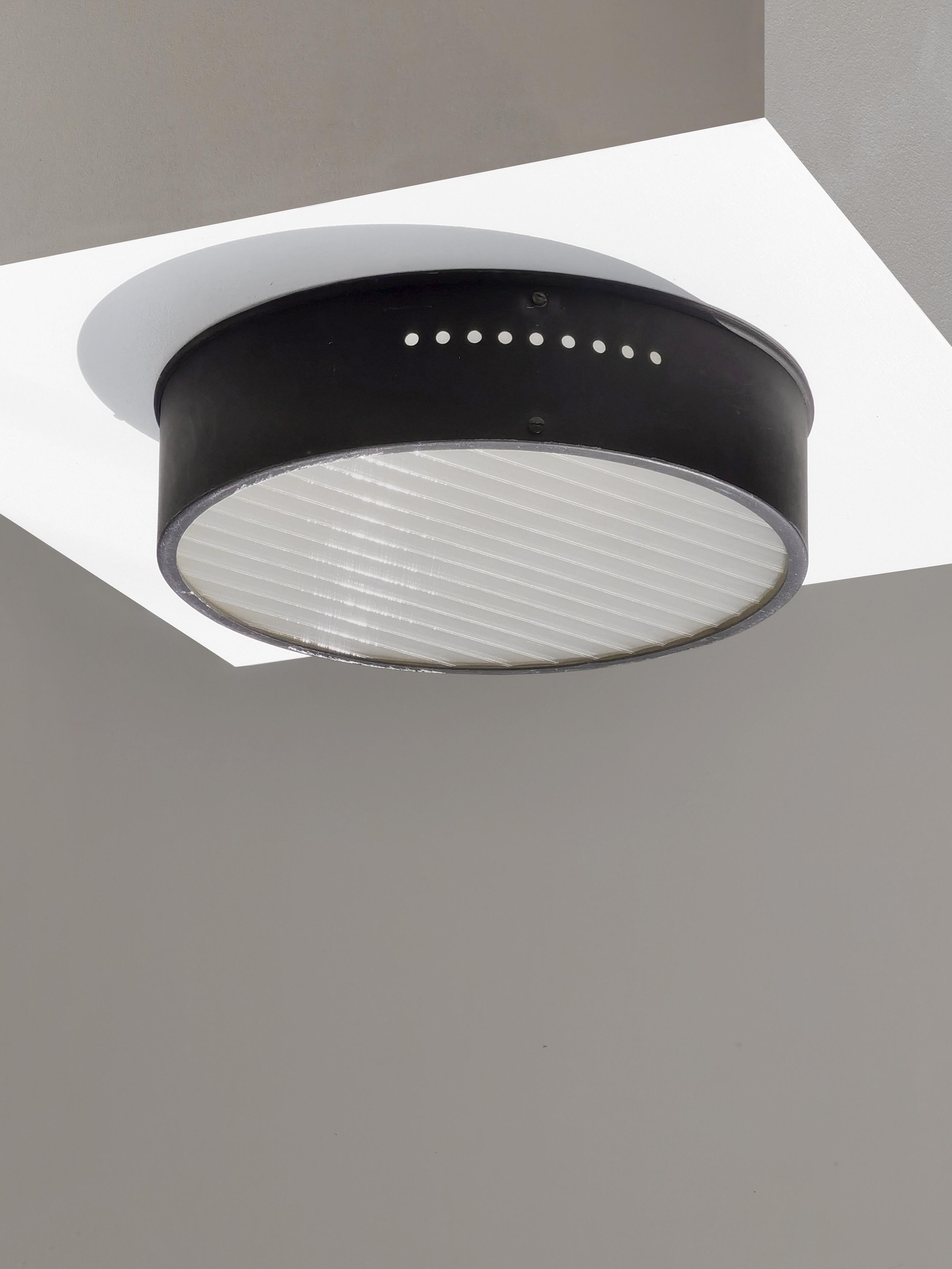 A simplistic and highly graphic Mid-Century-Modern, Modernist, Minimalist, circular ceiling fixture, black lacquered metal circular structure with 2 lines of round holes on each side giving this piece a strong visual presence, with its original