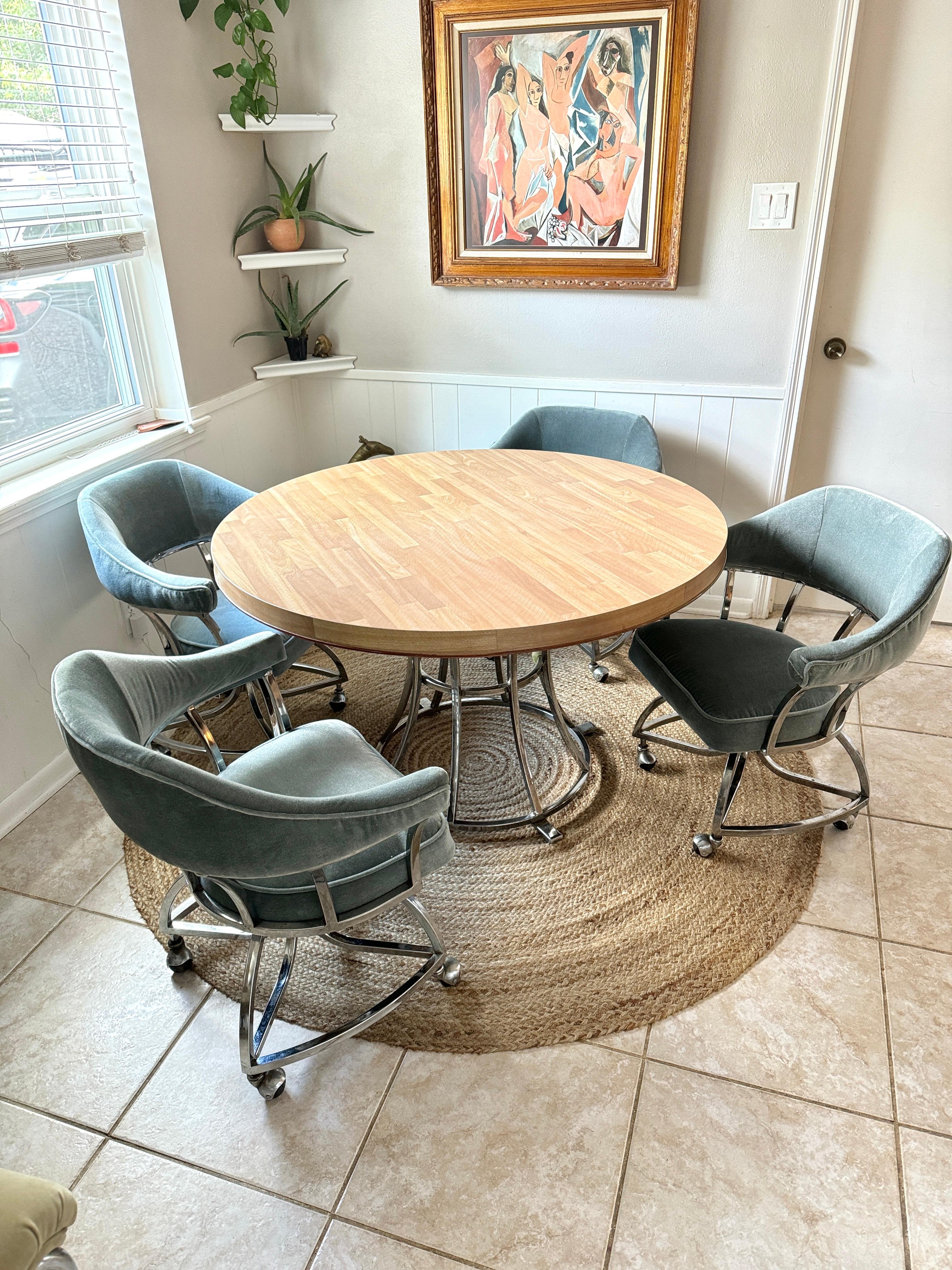 A mid century modern chrome dining set including 4 chairs on casters and a table, circa 1980s. Chairs have been recently recovered in a velvet fabric by Pollack. The chairs are ridiculously comfortable and this set is in very good condition. 

Table