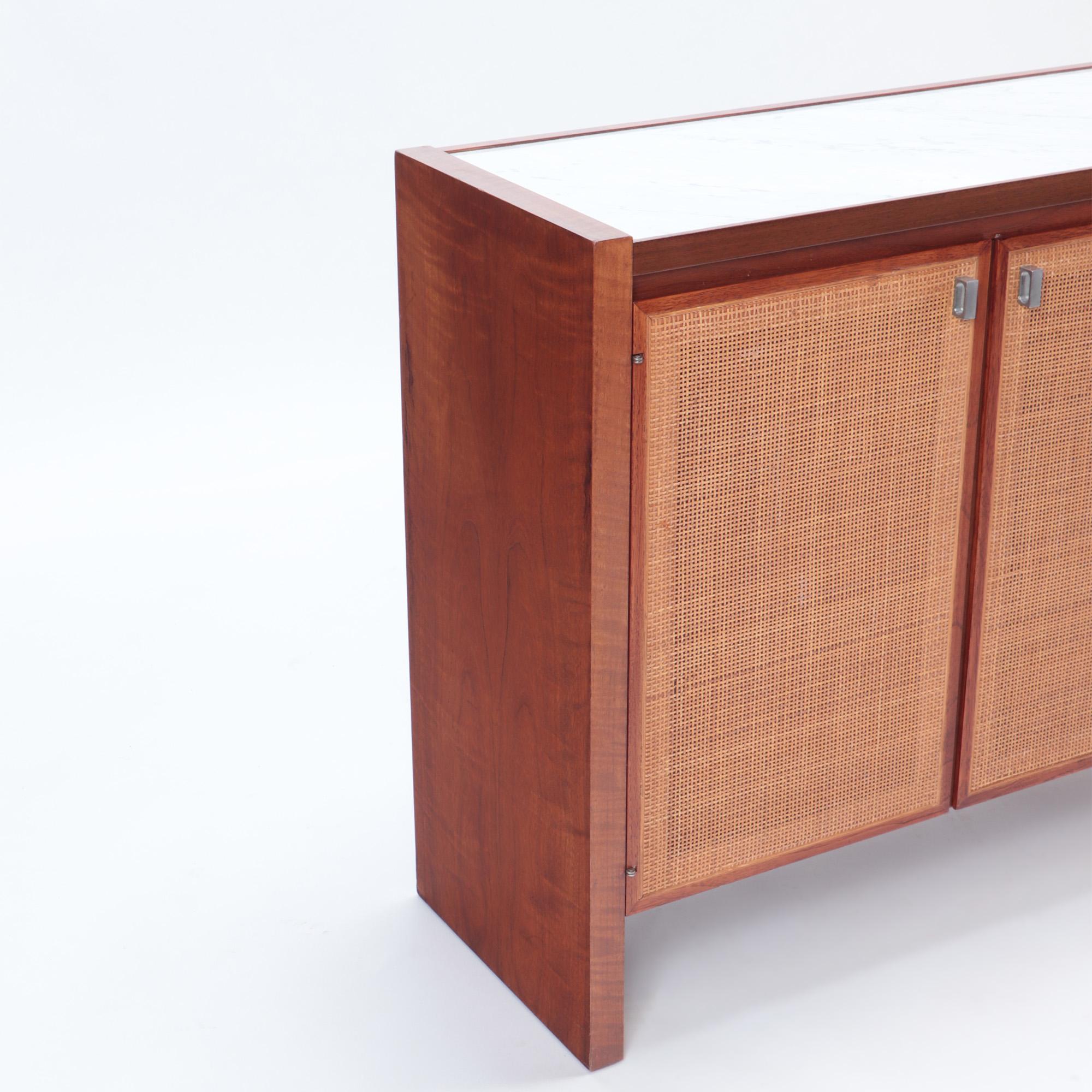 A Mid-Century Modern credenza, American, circa 1960. Designed by Jack Cartwright for Founders Furniture Co ( Manufacture). Walnut and Cane doors with stone top of a later replacement.