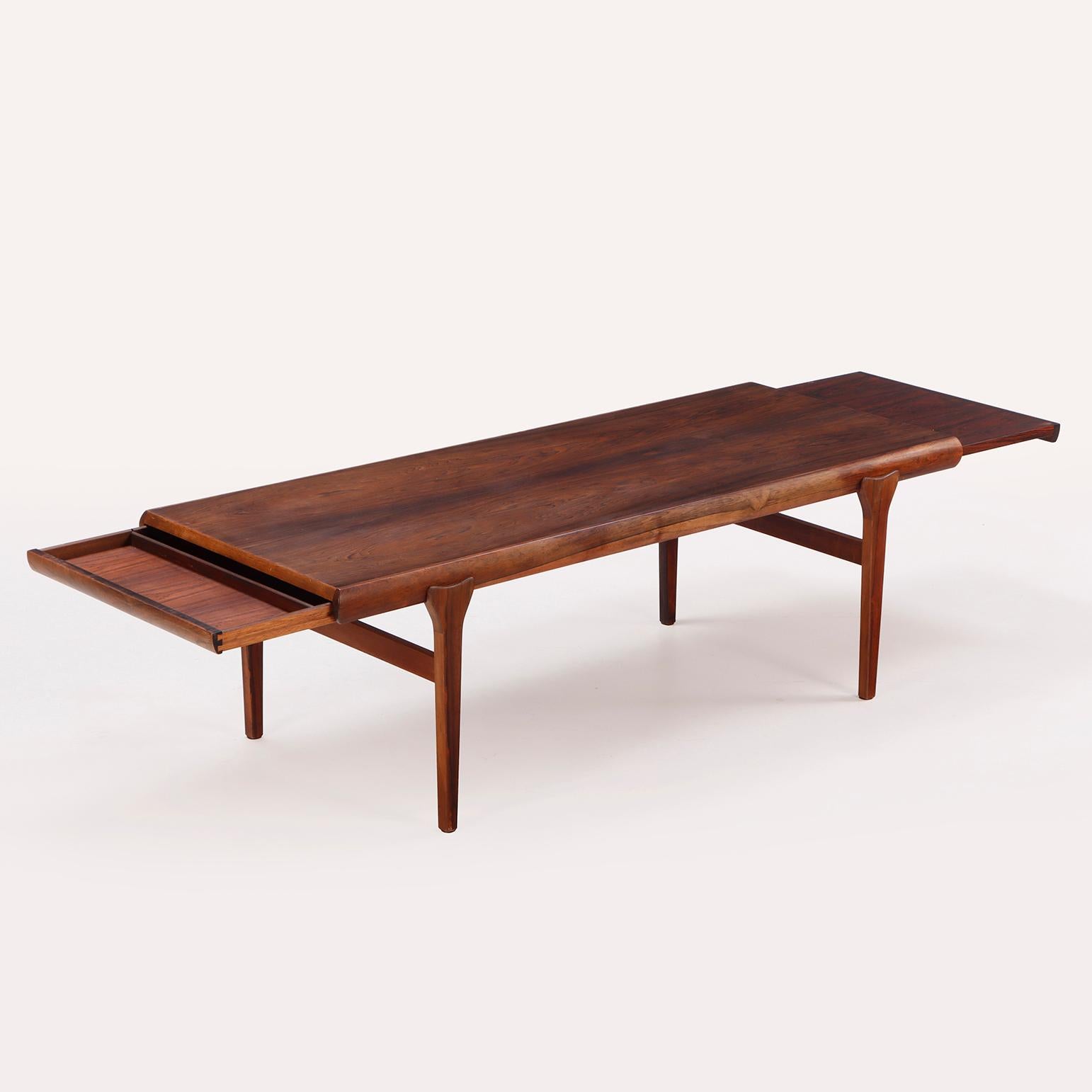 A mid century modern Danish rosewood coffee table by Johannes Andersen for Uldum Møbelfabrik circa 1960. Having pull-out slides on each side of table.