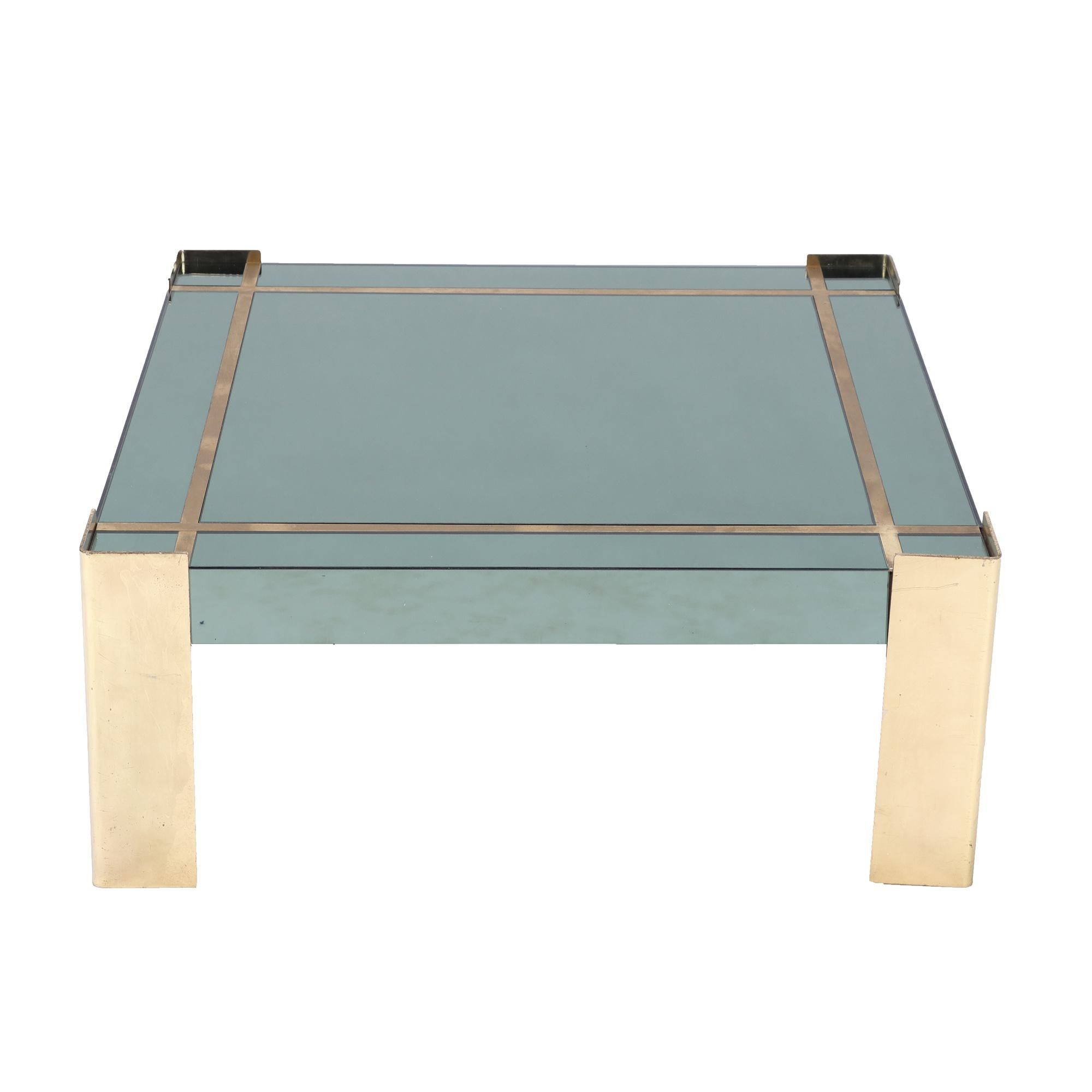 A Mid-Century Modern green glass top coffee table with brass legs and trim. Circa 1970.
Glass chipped on one corner of table.