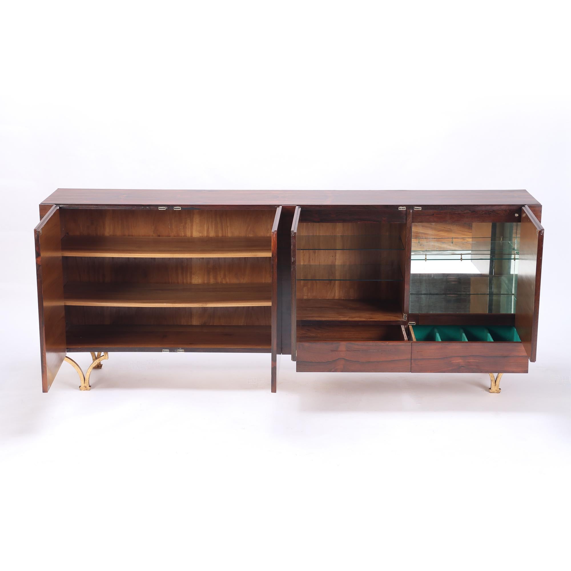 A Mid-Century Modern Italian four door rosewood sideboard, with gilt iron feet. Circa 1960. One drawer has defined compartments with felt, one cabinet fitted with glass shelves.
