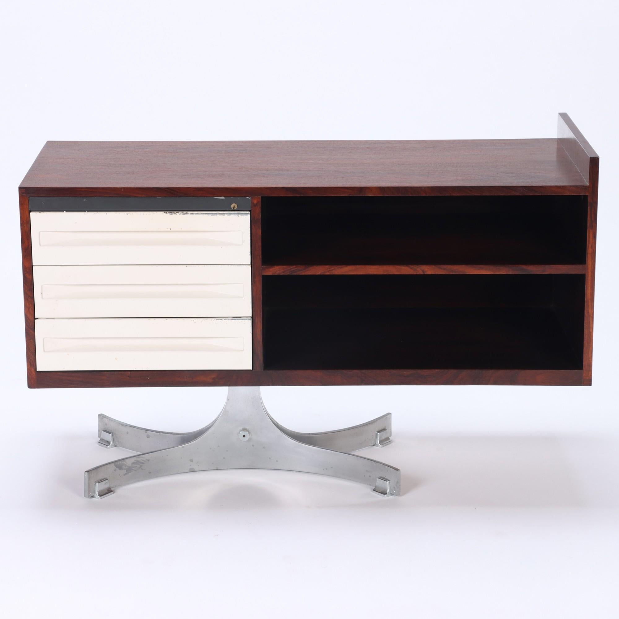 A Mid Century Modern Italian two part L shaped desk, rosewood with metal drawers. The desks rest on a base of curved metal legs. The smaller desk offers two open shelves and three drawers for storage (28